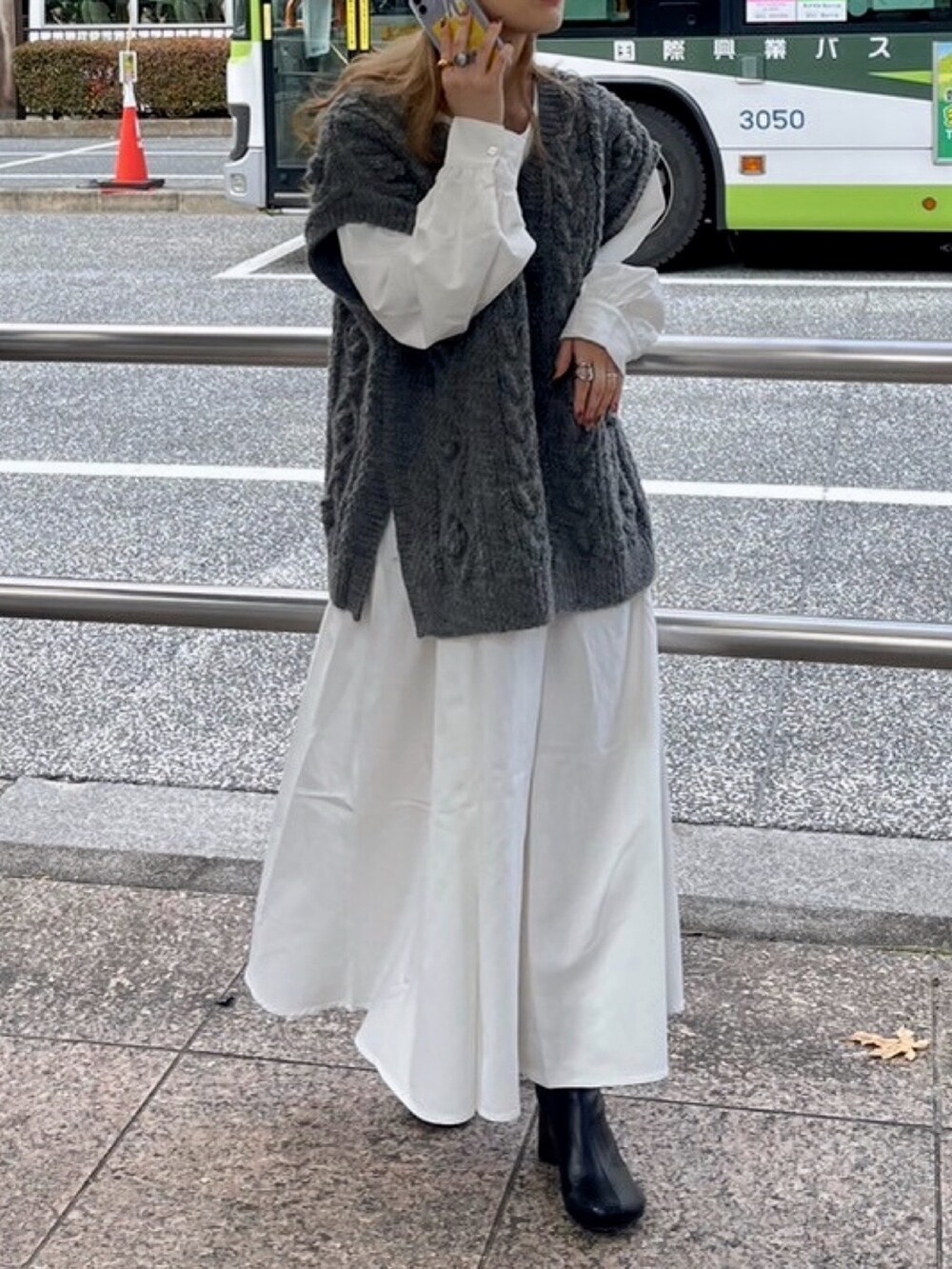 グレー系のニット/セーター、ブラック系のブーツ、ブラック系のワンピースを着用したレディースの冬コーディネートの5枚目の写真