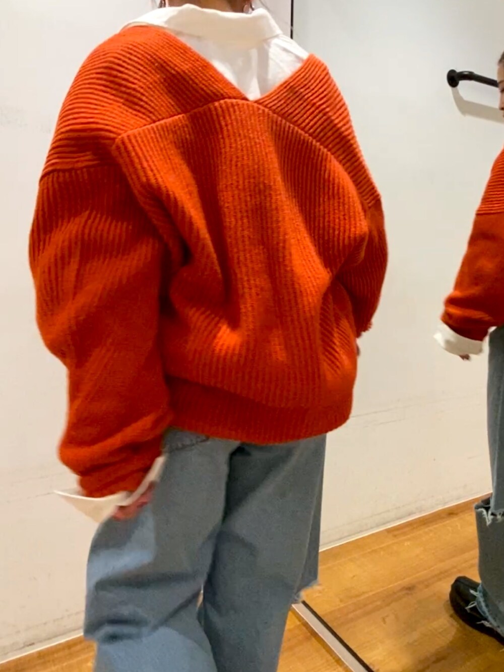 オレンジ系のニット/セーター、ホワイト系のシャツ/ブラウス、ブルー系のデニムパンツを着用したレディースの秋コーディネートの3枚目の写真