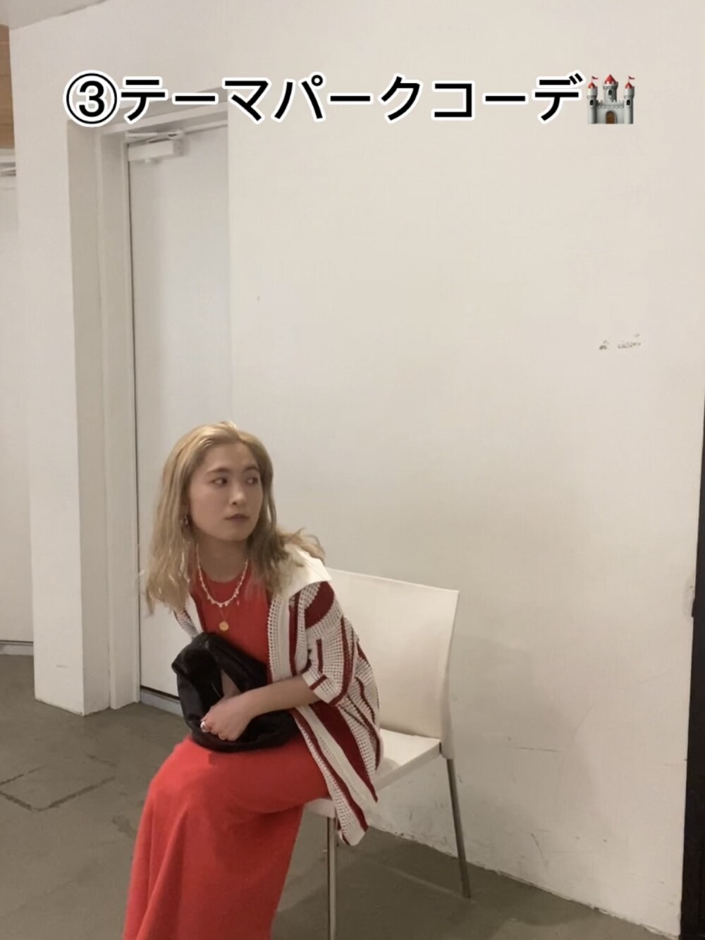 ブラック系のハンドバッグ、オレンジ系のワンピース、レッド系のカーディガン/ボレロを着用したレディースの春コーディネートの2枚目の写真