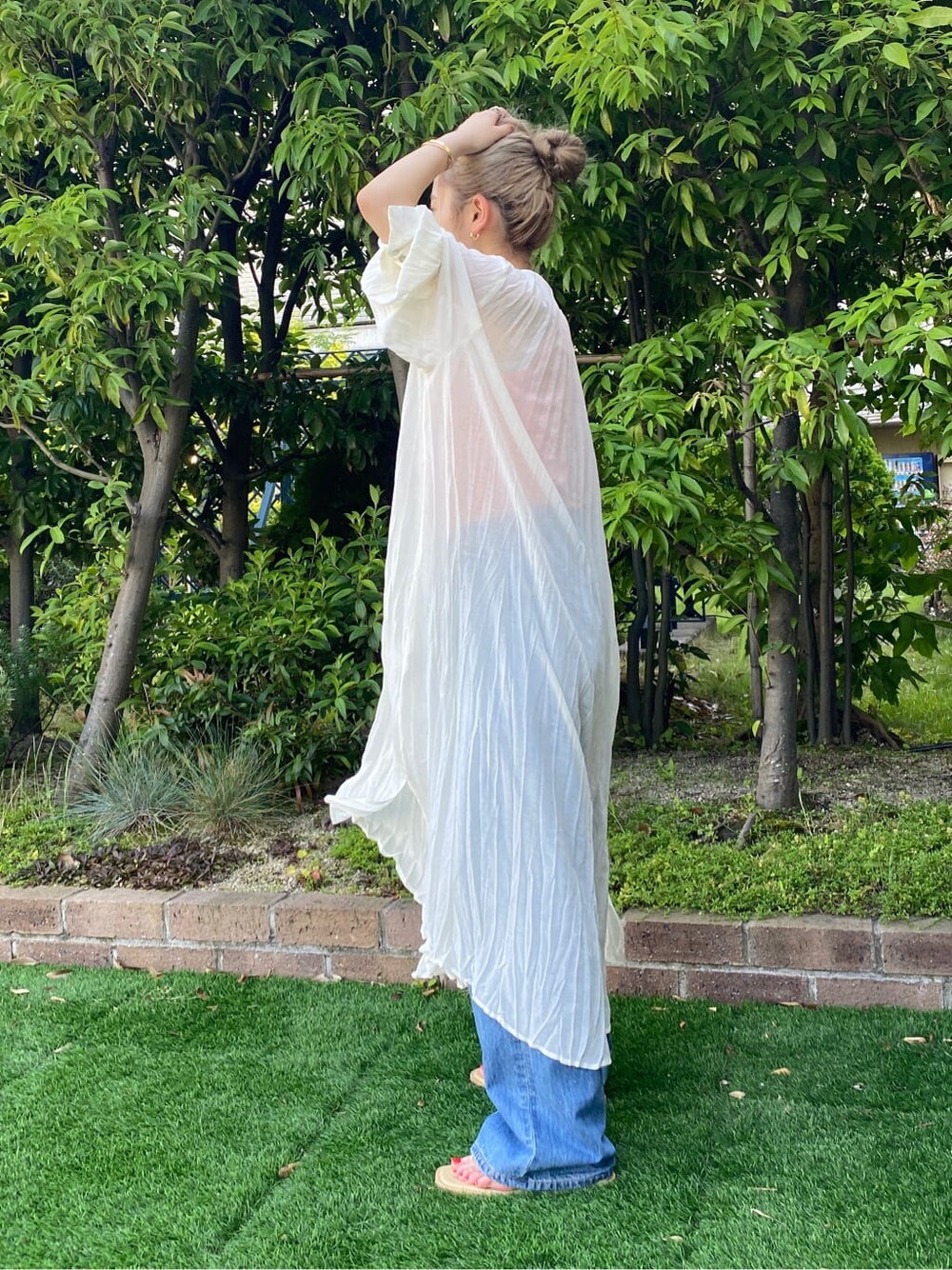 グリーン系のサンダル、ブルー系のデニムパンツ、ホワイト系のスニーカーを着用したレディースの夏コーディネートの4枚目の写真