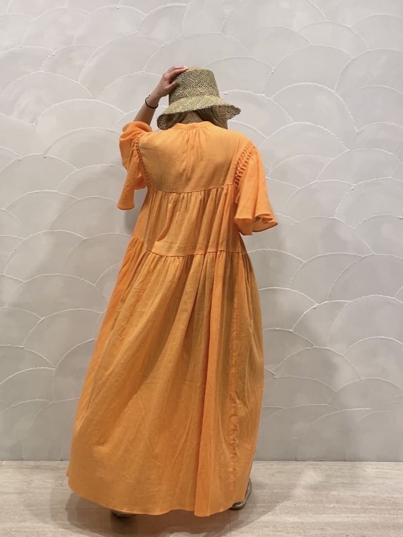 オレンジ系のワンピース、ベージュ系のハットを着用したレディースの春コーディネートの3枚目の写真