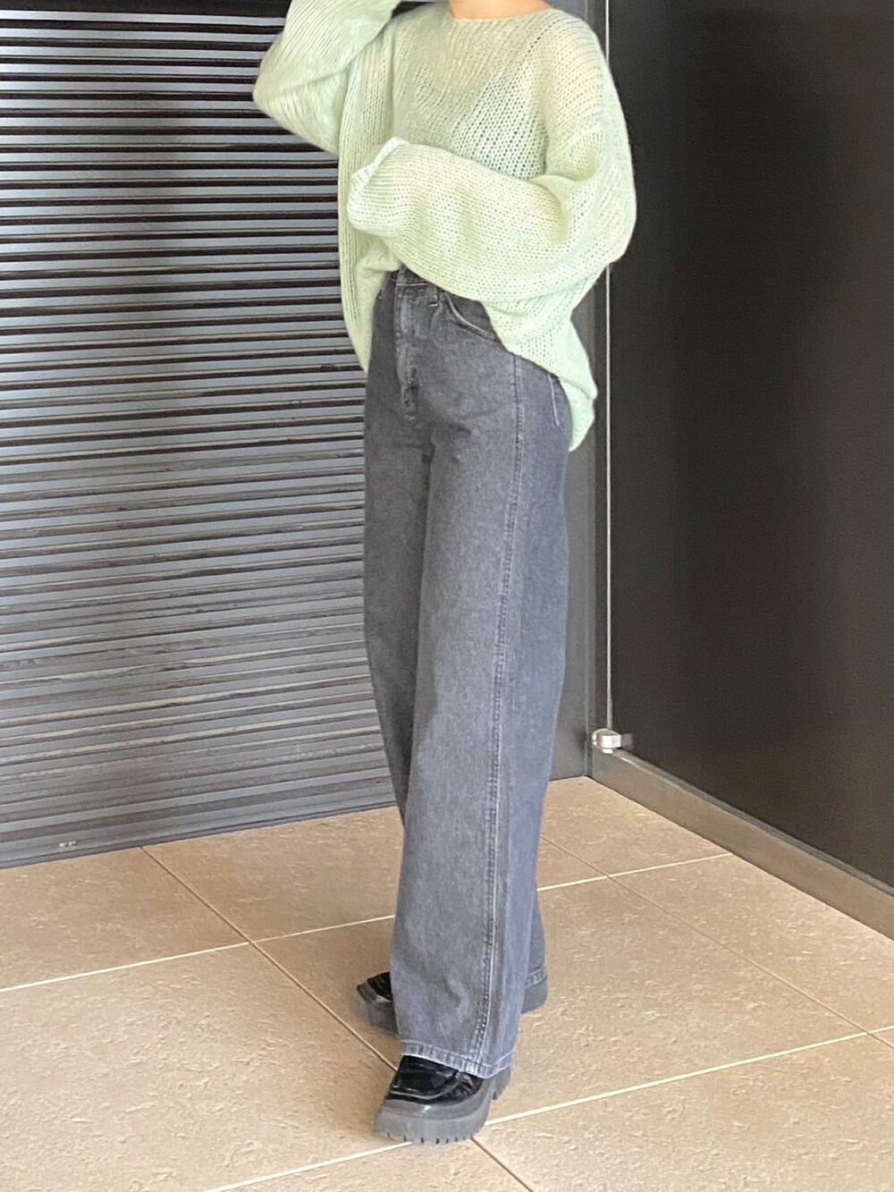 グリーン系のニット/セーター、ブラック系のデニムパンツを着用したレディースの冬コーディネートの5枚目の写真