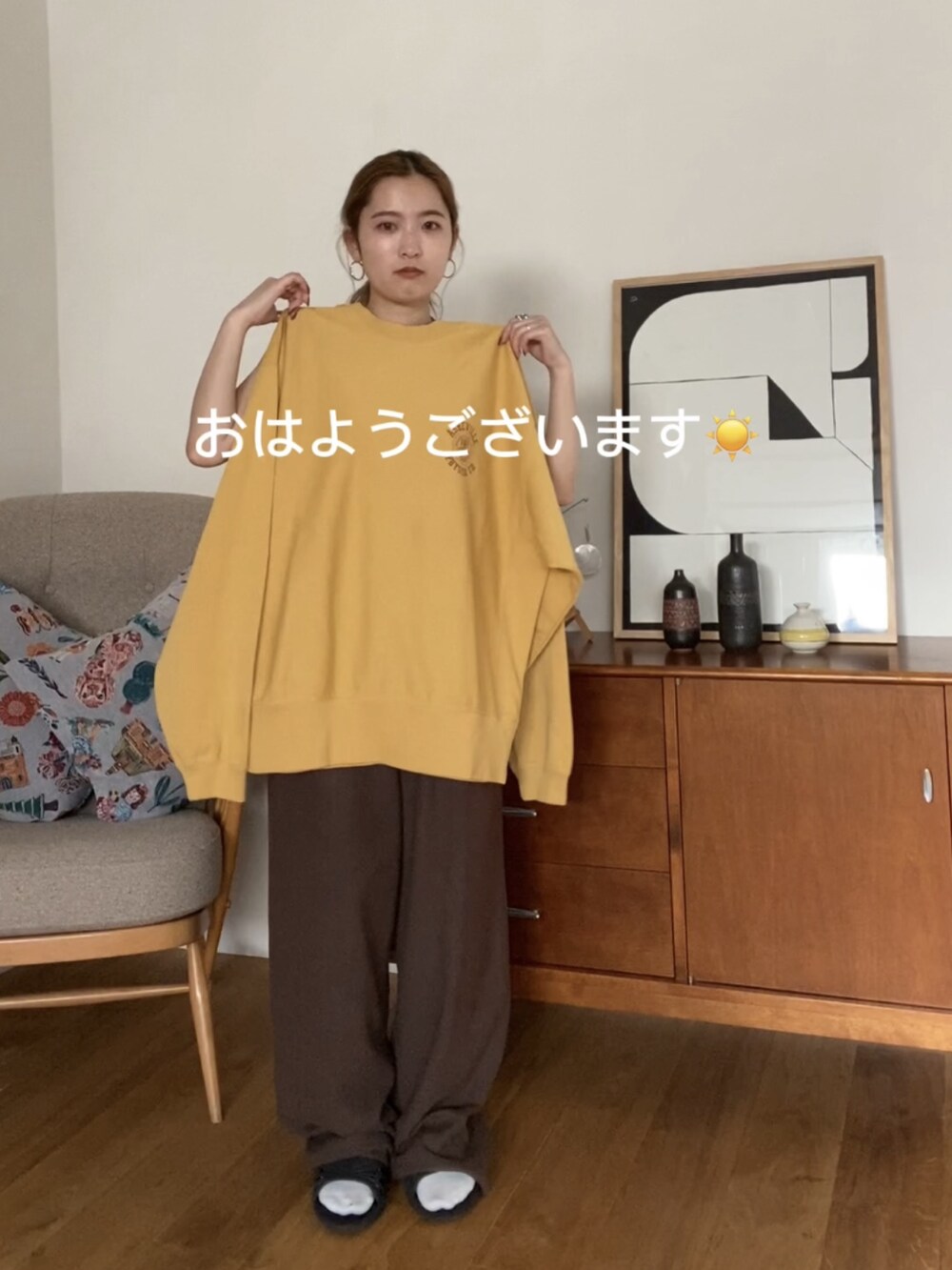 イエロー系のスウェット、ブラック系のニットキャップ/ビーニー、ブラウン系のメガネを着用したレディースの冬コーディネートの2枚目の写真