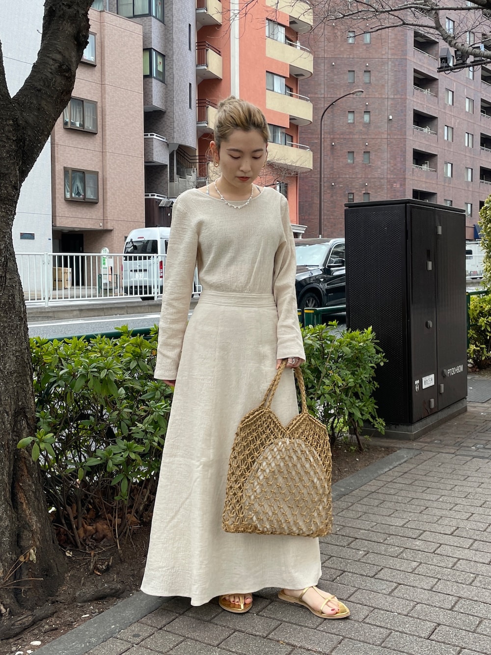 ホワイト系のワンピース、イエロー系のハンドバッグ、ゴールド系のサンダルを着用したレディースの春コーディネートの4枚目の写真