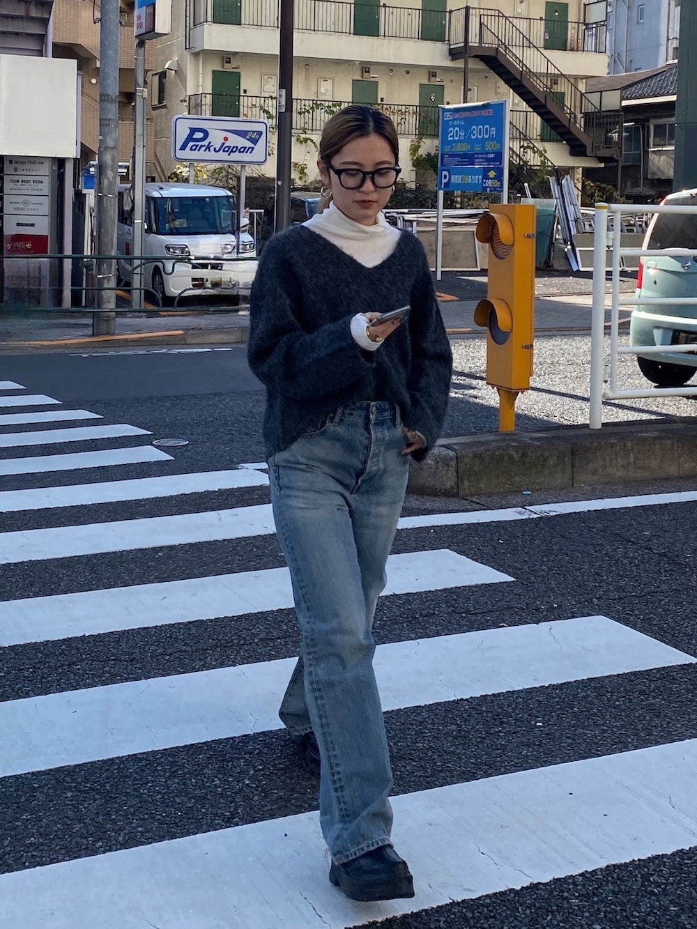 グレー系のニット/セーター、ブルー系のデニムパンツ、ブラック系のブーツを着用したレディースの冬コーディネートの2枚目の写真