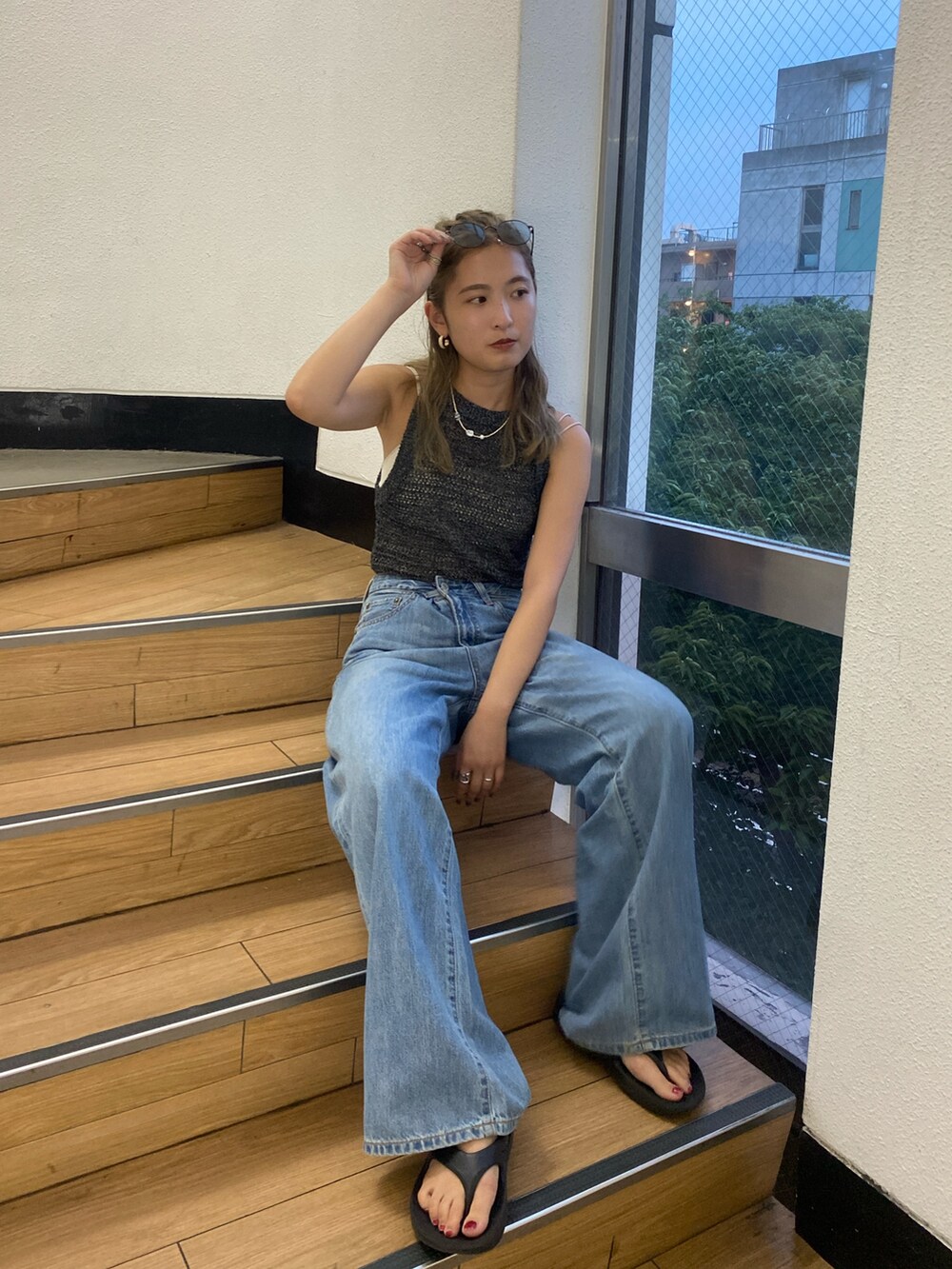 ブラック系のニット/セーター、ホワイト系のキャミソール、ブルー系のデニムパンツを着用したレディースの夏コーディネートの3枚目の写真