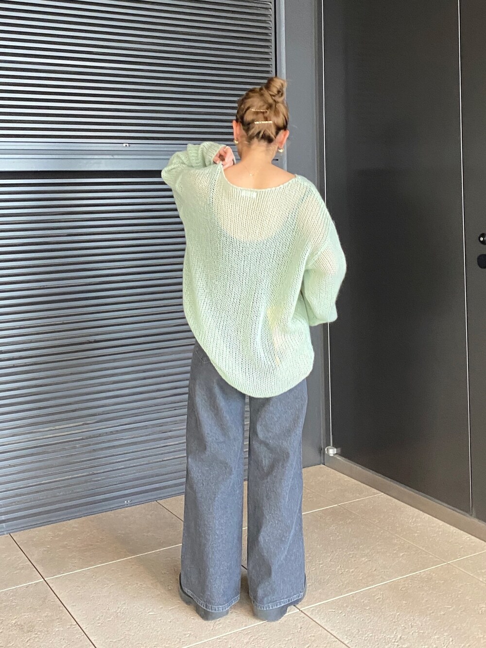 グリーン系のニット/セーター、ブラック系のデニムパンツを着用したレディースの冬コーディネートの4枚目の写真