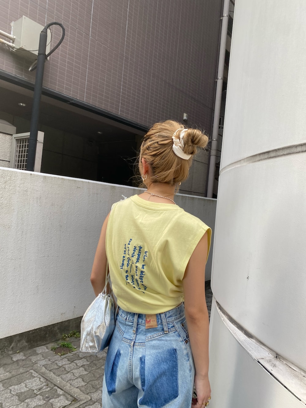 イエロー系のタンクトップ、ブルー系のデニムパンツ、ホワイト系のサンダルを着用したレディースの夏コーディネートの3枚目の写真