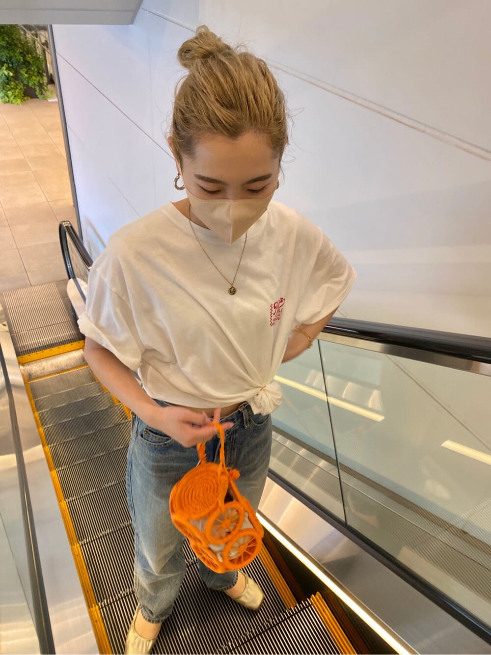 オレンジ系のかごバッグ、ホワイト系のTシャツ/カットソー、ブルー系のデニムパンツを着用したレディースの春コーディネートの6枚目の写真