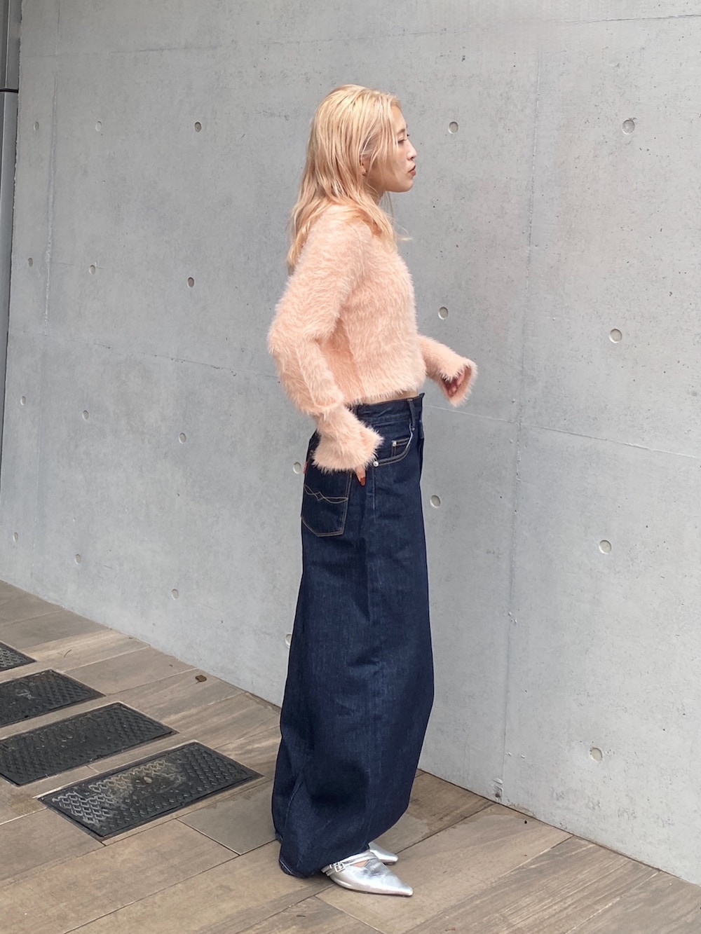 オレンジ系のカーディガン/ボレロ、ブルー系のデニムパンツ、シルバー系のパンプスを着用したレディースの秋コーディネートの2枚目の写真