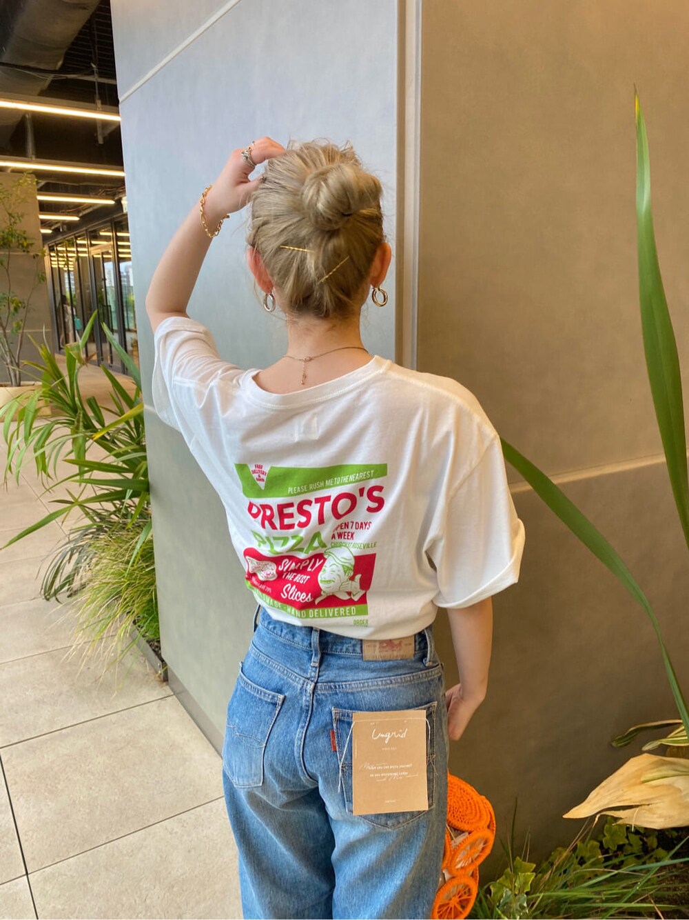 オレンジ系のかごバッグ、ホワイト系のTシャツ/カットソー、ブルー系のデニムパンツを着用したレディースの春コーディネートの4枚目の写真