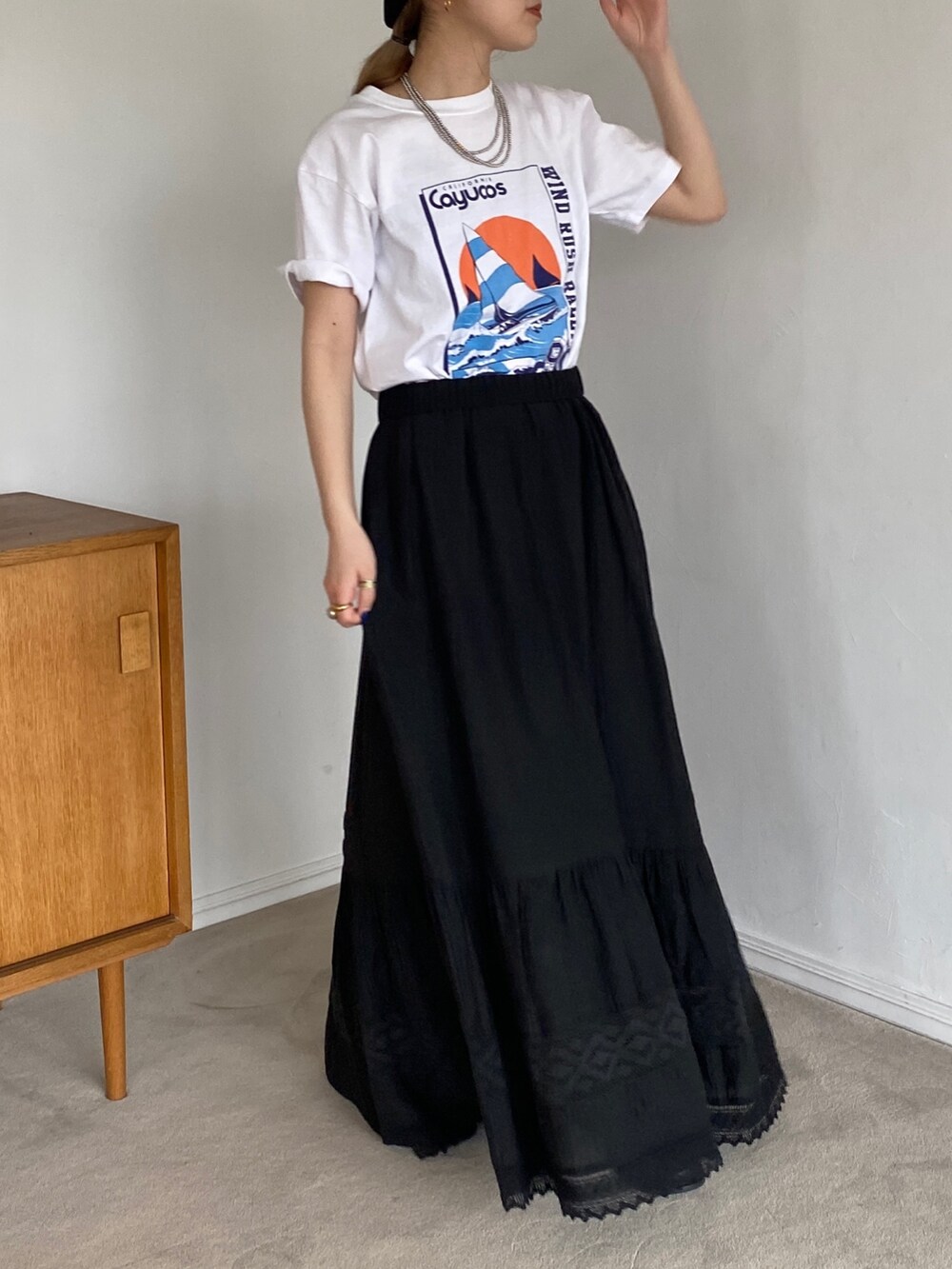 ホワイト系のTシャツ/カットソー、ブラック系のスカートを着用したレディースの春コーディネートの2枚目の写真