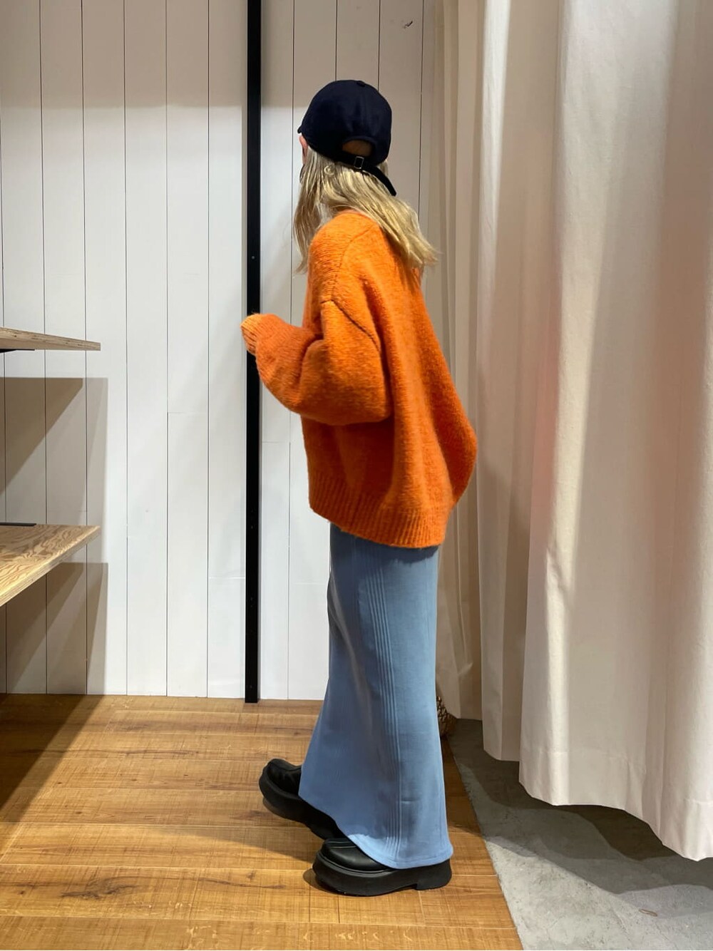 オレンジ系のカーディガン/ボレロ、ブラック系のブーツ、ブルー系のワンピースを着用したレディースの秋コーディネートの5枚目の写真