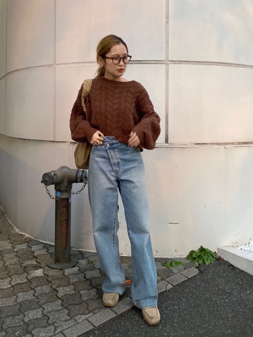 ブラウン系のニット/セーター、ブルー系のデニムパンツ、ベージュ系のハンドバッグを着用したレディースの冬コーディネートの7枚目の写真