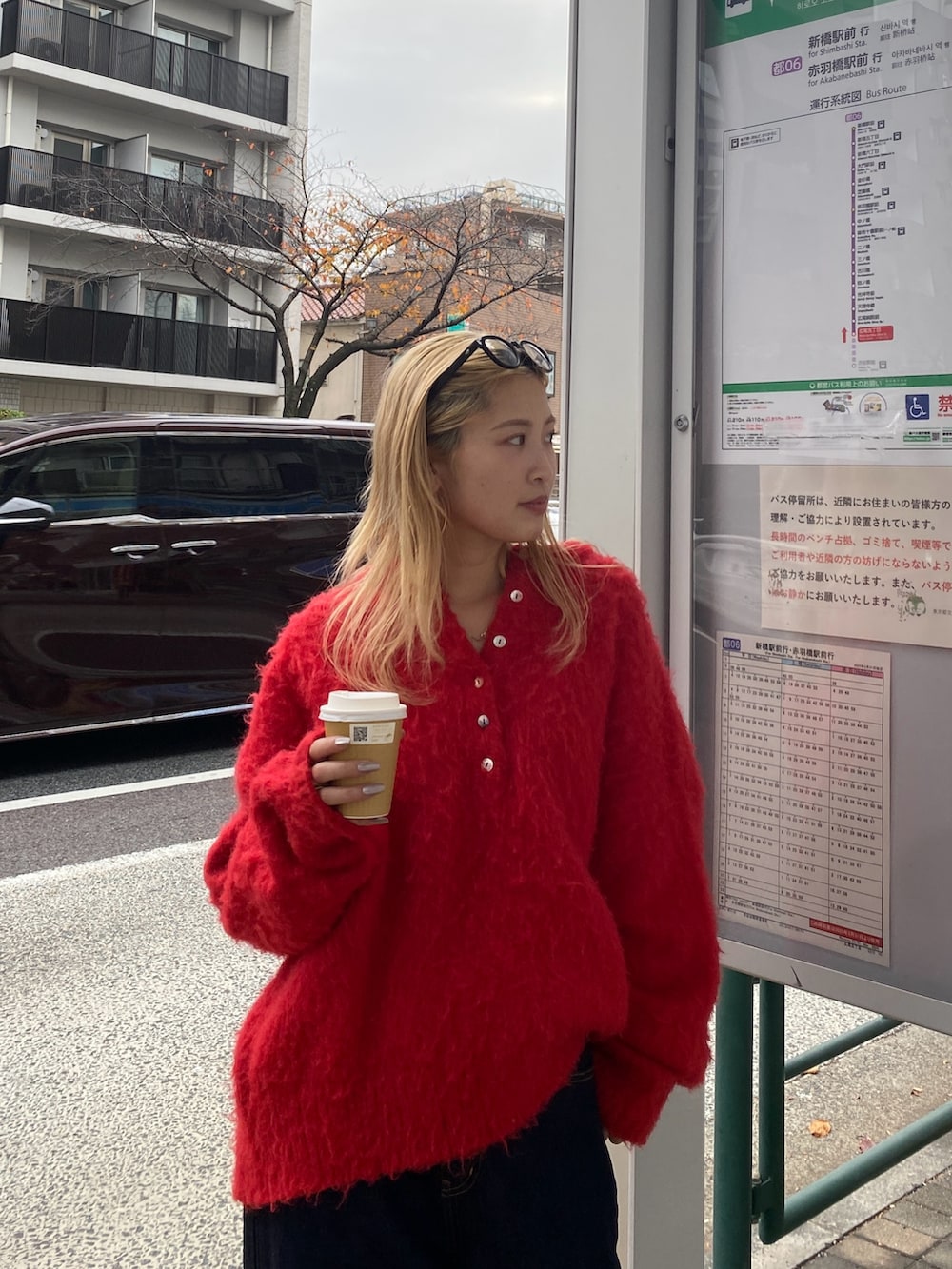 レッド系のニット/セーター、ブルー系のデニムパンツを着用したレディースの冬コーディネートの4枚目の写真