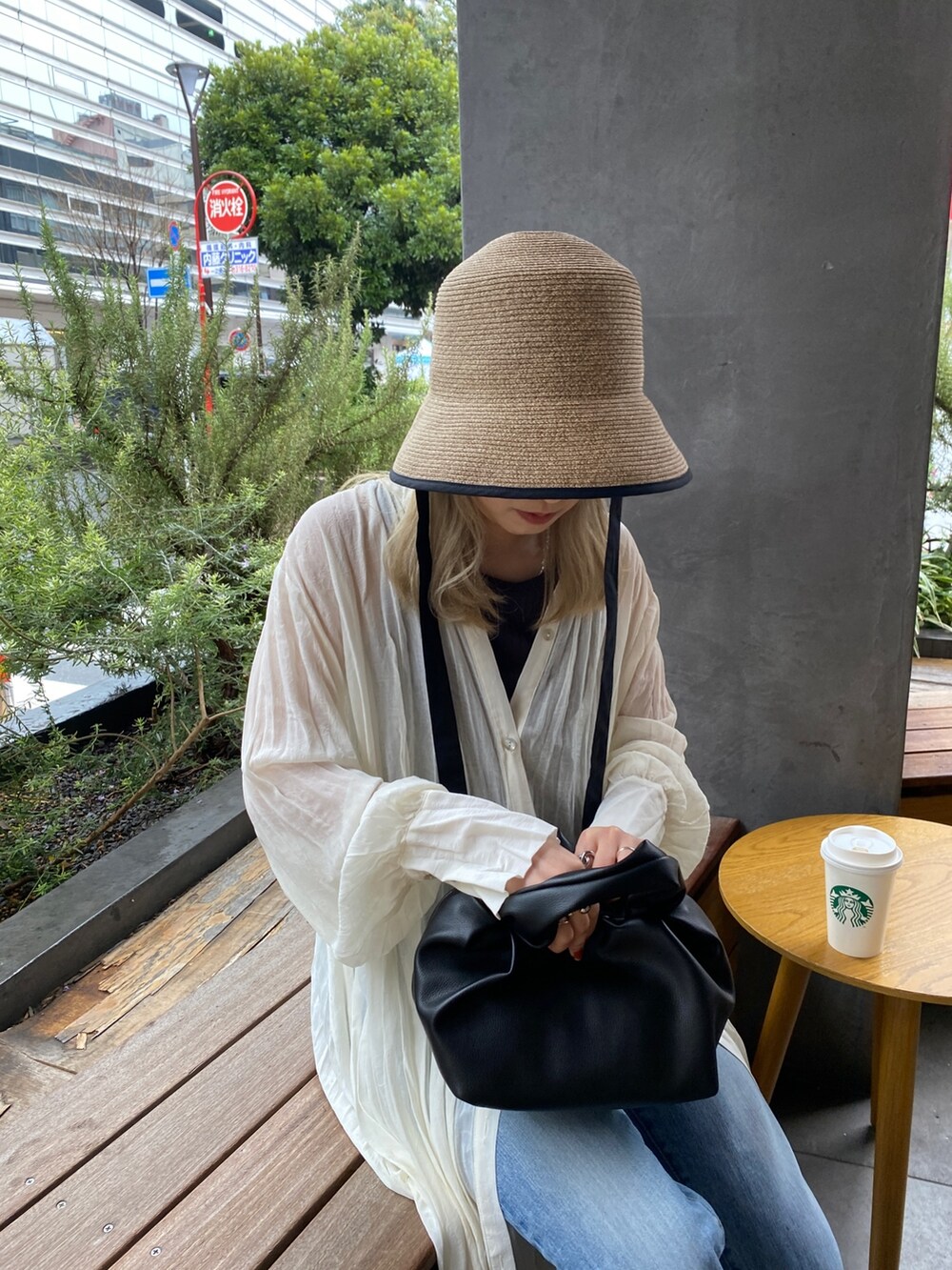 ホワイト系のワンピース、ブルー系のデニムパンツ、ブラック系のハンドバッグを着用したレディースの春コーディネートの4枚目の写真