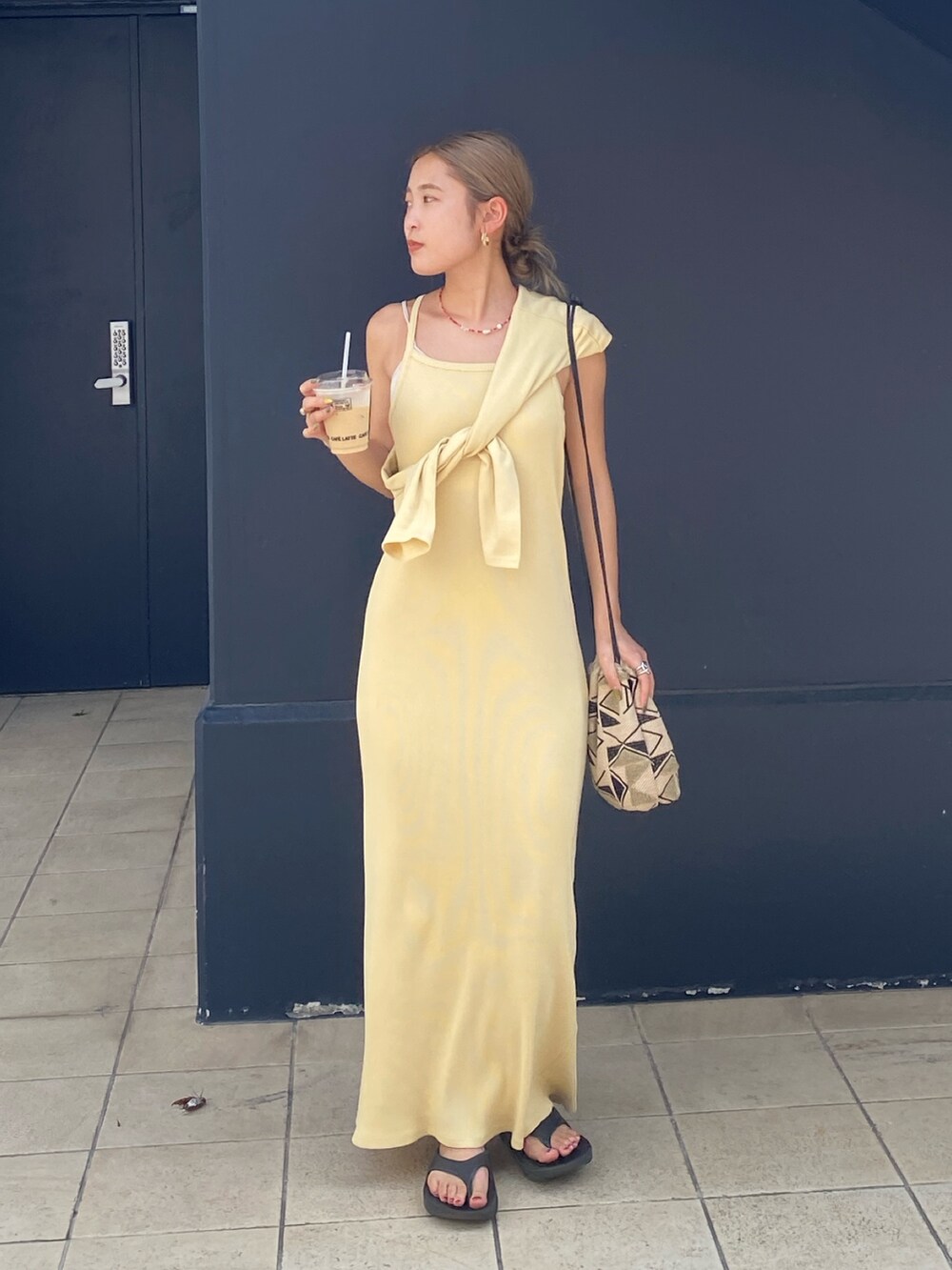 イエロー系のワンピース、レッド系のネックレスを着用したレディースの夏コーディネートの2枚目の写真