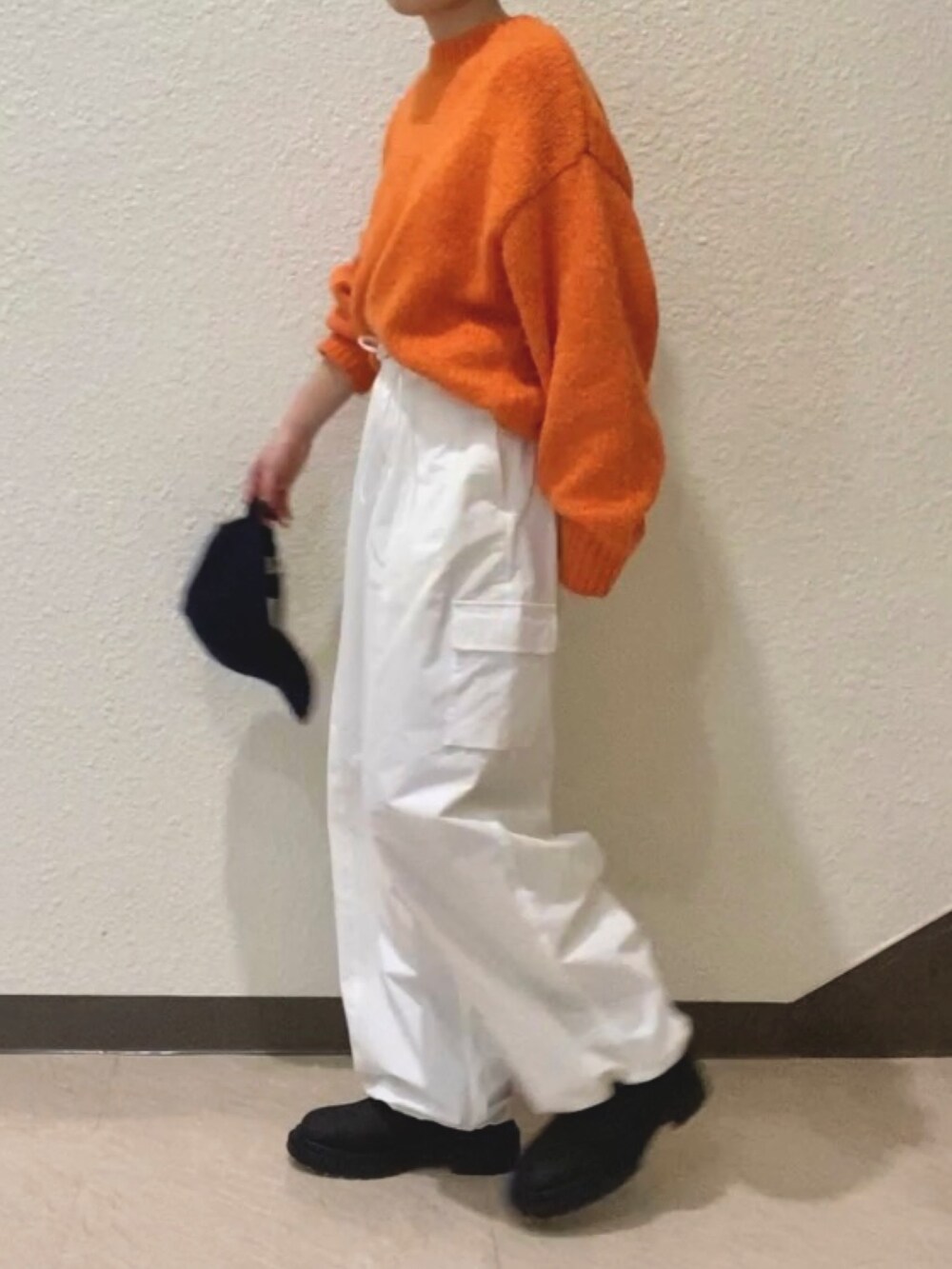 オレンジ系のニット/セーター、ホワイト系のカーゴパンツ、ブラック系のブーツを着用したレディースの冬コーディネートの4枚目の写真