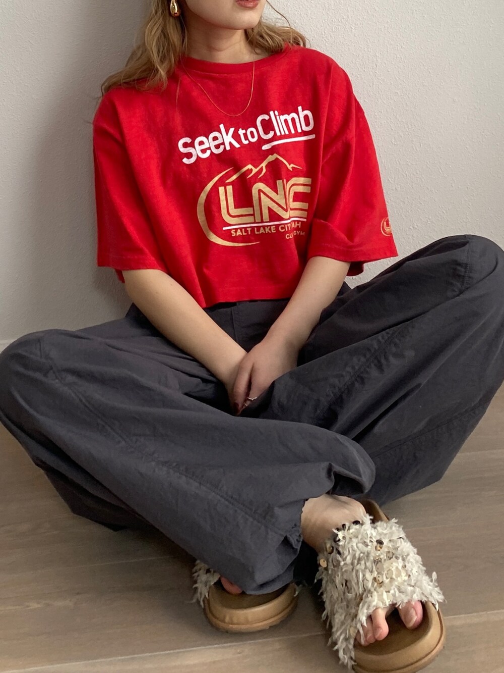 レッド系のTシャツ/カットソー、グレー系のその他パンツ、ホワイト系のサンダルを着用したレディースの冬コーディネートの3枚目の写真