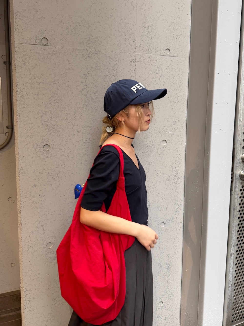 ブラック系のTシャツ/カットソー、レッド系のキャップを着用したレディースの夏コーディネートの6枚目の写真