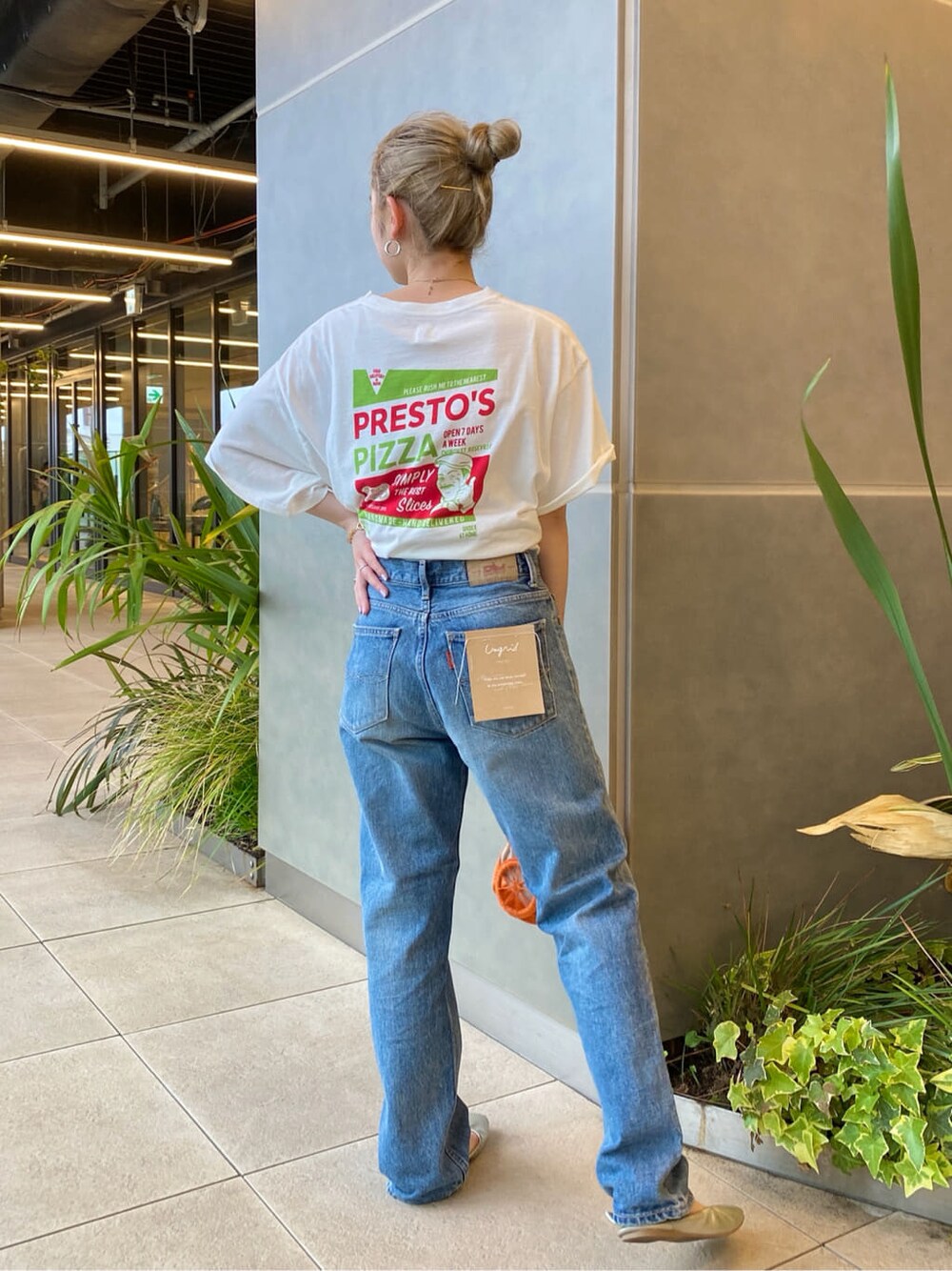 オレンジ系のかごバッグ、ホワイト系のTシャツ/カットソー、ブルー系のデニムパンツを着用したレディースの春コーディネートの2枚目の写真