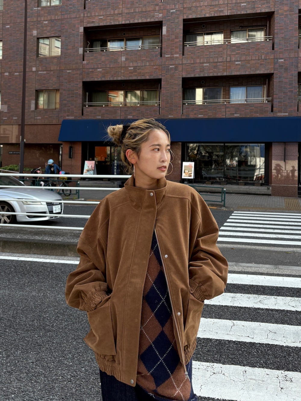 ブラウン系のブルゾン、ブラウン系のニット/セーター、ブルー系のデニムパンツを着用したレディースの秋コーディネートの2枚目の写真