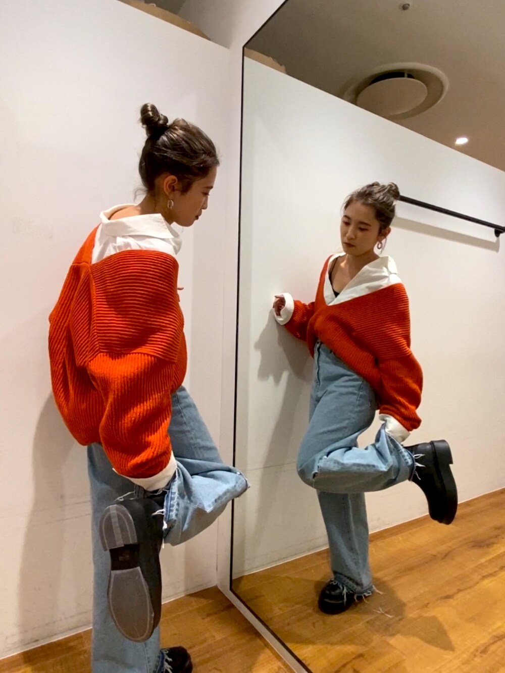 オレンジ系のニット/セーター、ホワイト系のシャツ/ブラウス、ブルー系のデニムパンツを着用したレディースの秋コーディネートの2枚目の写真