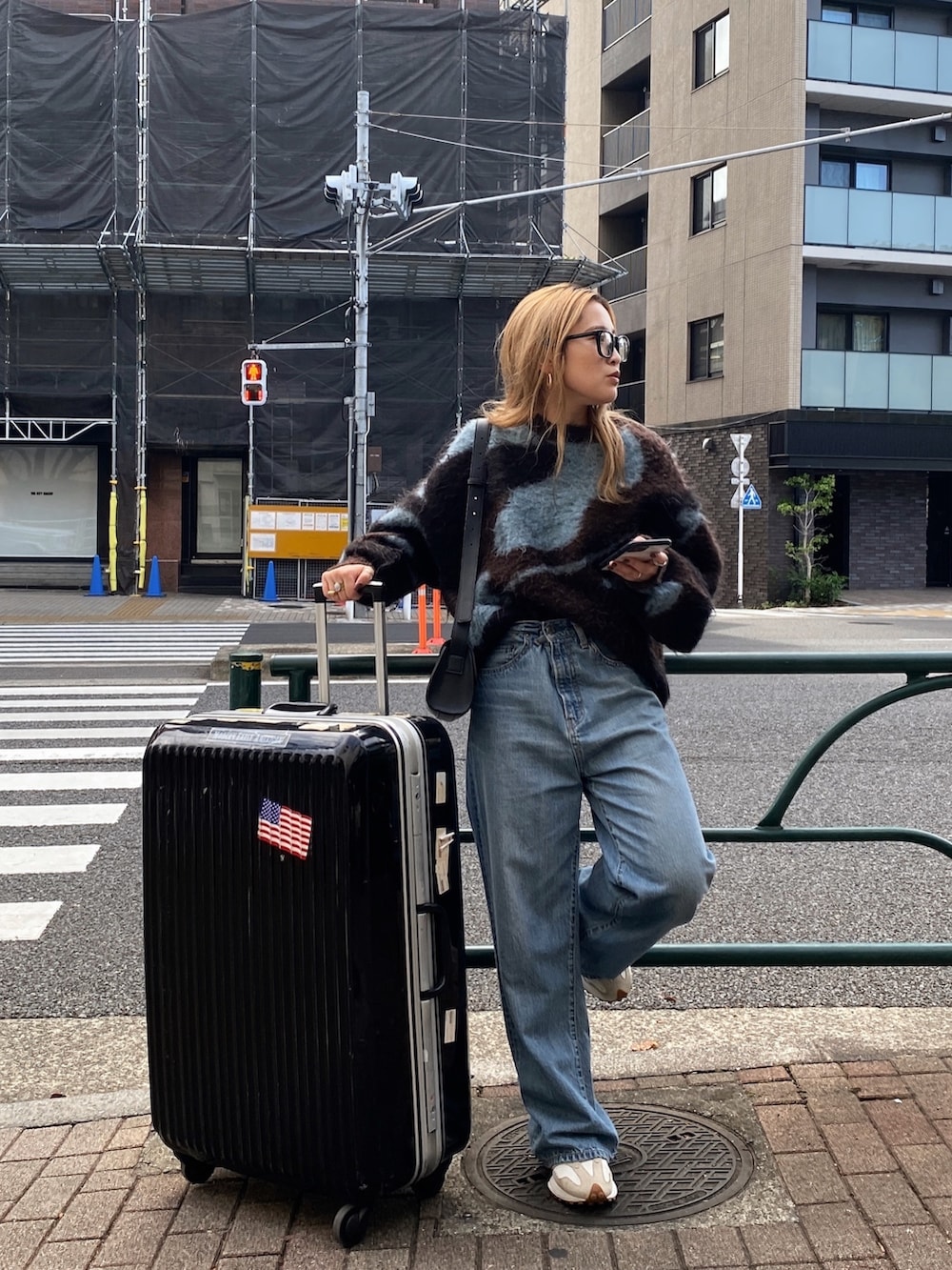 ブラウン系のニット/セーター、ブルー系のデニムパンツ、ブラック系のメガネを着用したレディースの秋コーディネートの6枚目の写真