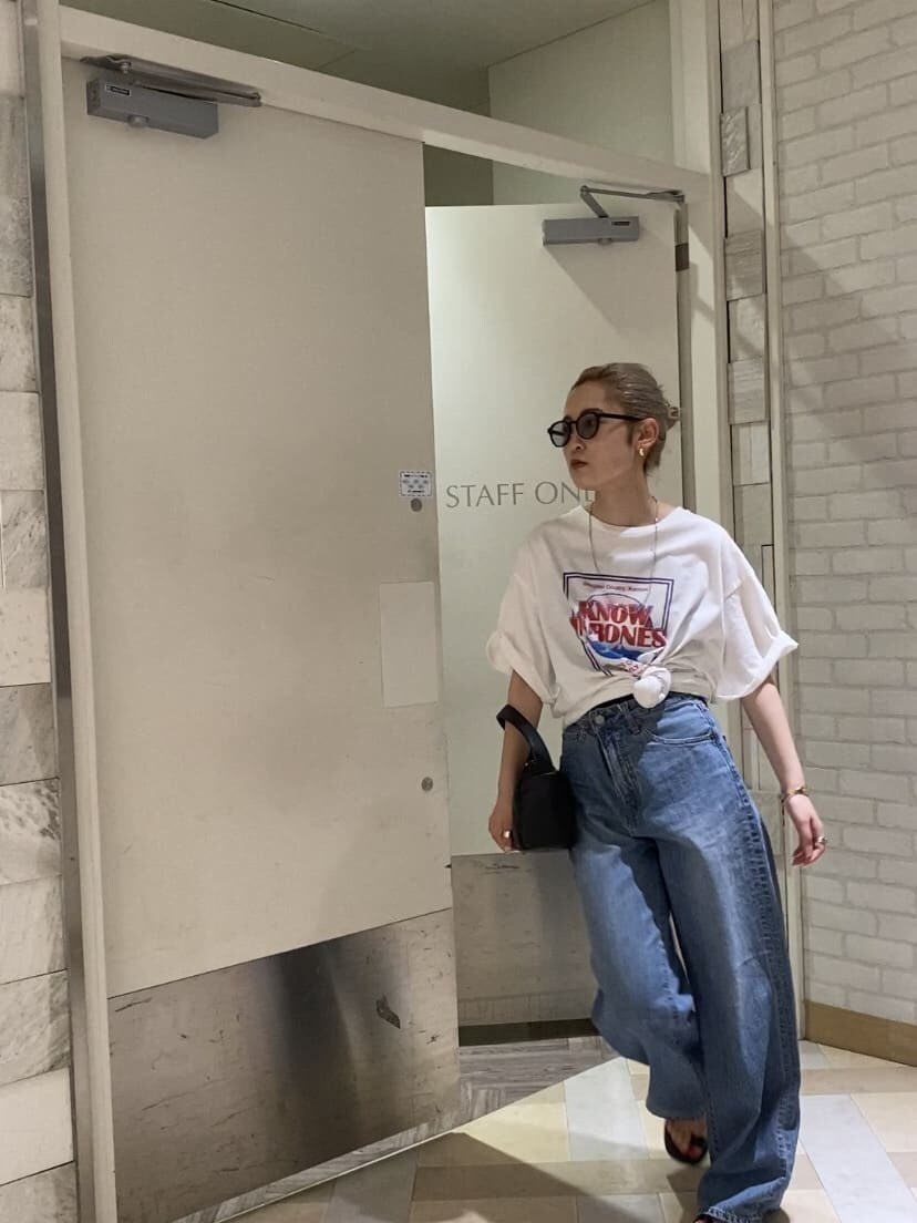 ブルー系のデニムパンツ、ホワイト系のTシャツ/カットソー、ブラック系のサンダルを着用したレディースの夏コーディネートの2枚目の写真