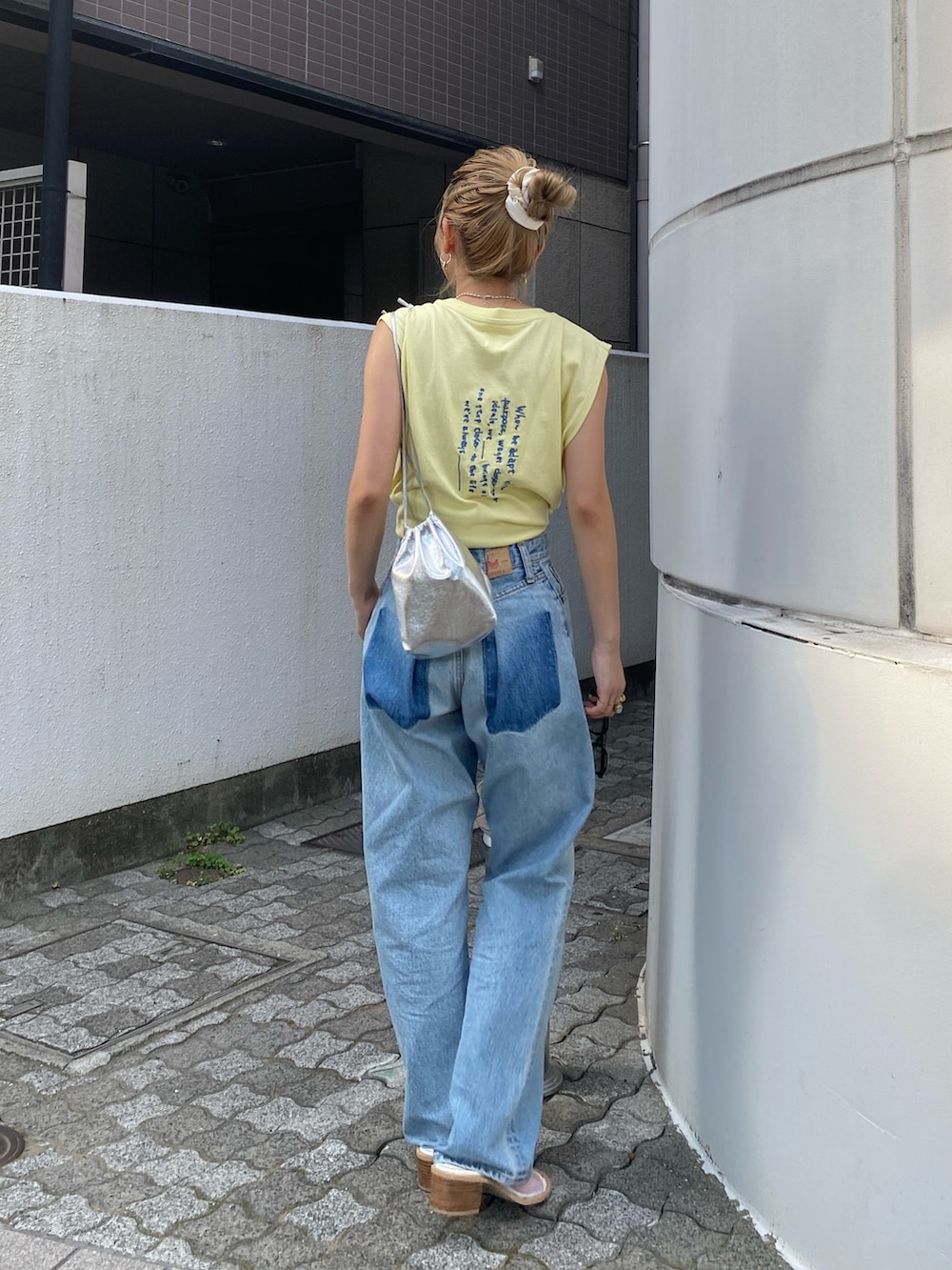 イエロー系のタンクトップ、ブルー系のデニムパンツ、ホワイト系のサンダルを着用したレディースの夏コーディネートの4枚目の写真