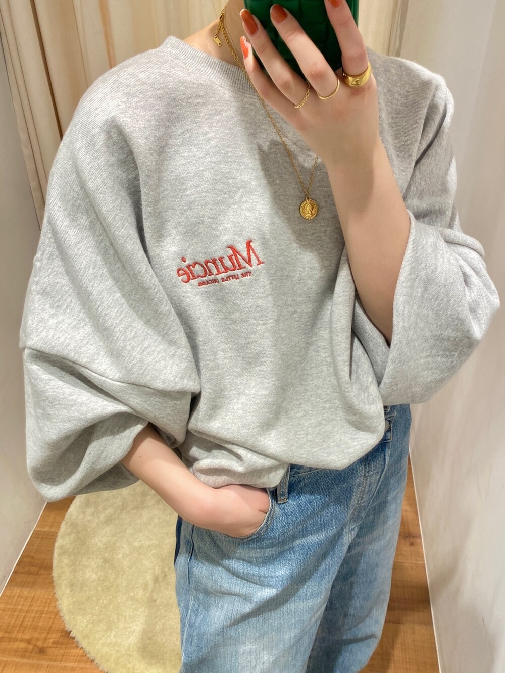 グレー系のスウェット、ブルー系のデニムパンツを着用したレディースの冬コーディネートの2枚目の写真
