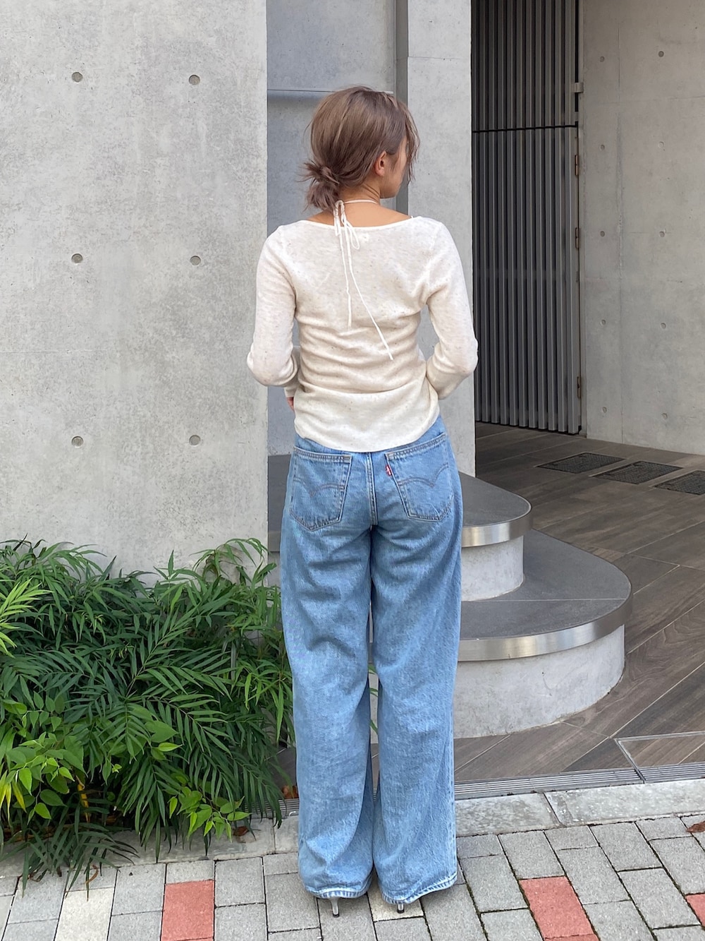 ホワイト系のニット/セーター、ブルー系のデニムパンツ、シルバー系のパンプスを着用したレディースの夏コーディネートの3枚目の写真