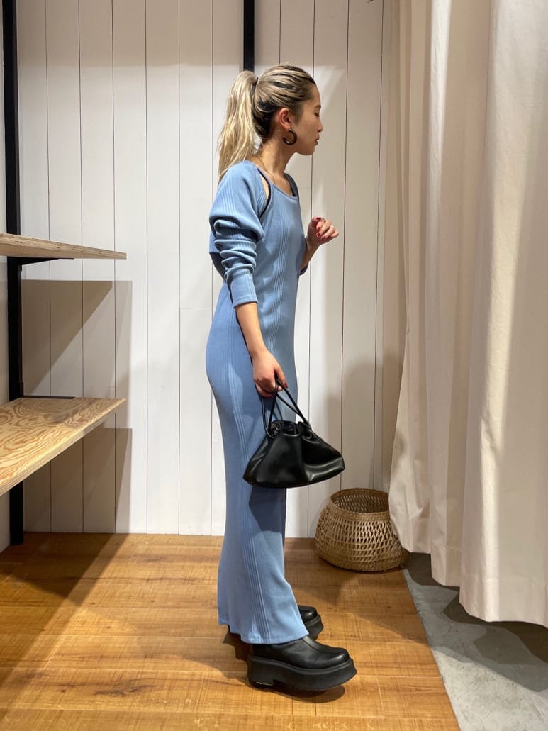 ブラック系のブーツ、ブルー系のワンピース、ブラック系のクラッチバッグを着用したレディースの秋コーディネートの2枚目の写真