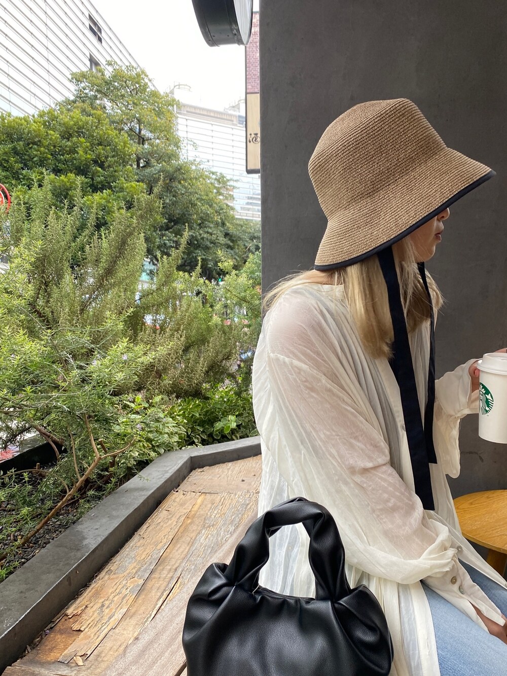 ホワイト系のワンピース、ブルー系のデニムパンツ、ブラック系のハンドバッグを着用したレディースの春コーディネートの5枚目の写真