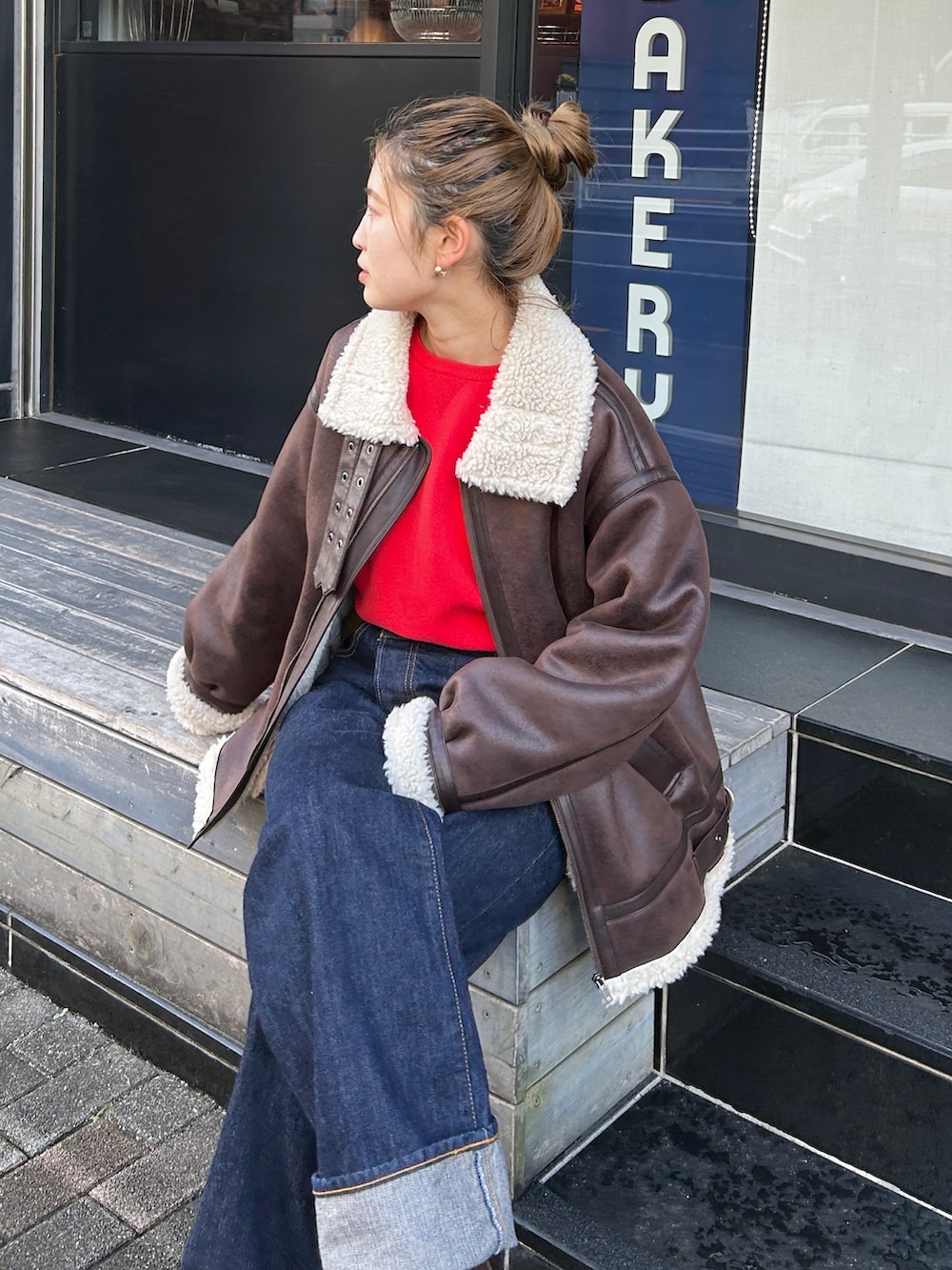 レッド系のニット/セーター、ブラウン系のブルゾン、ブルー系のデニムパンツを着用したレディースの冬コーディネートの4枚目の写真