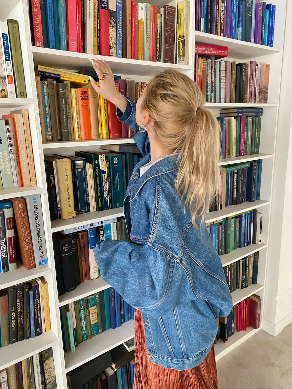 ブルー系のデニムジャケット、オレンジ系のワンピース、ブラック系のブーツを着用したレディースの秋コーディネートの2枚目の写真