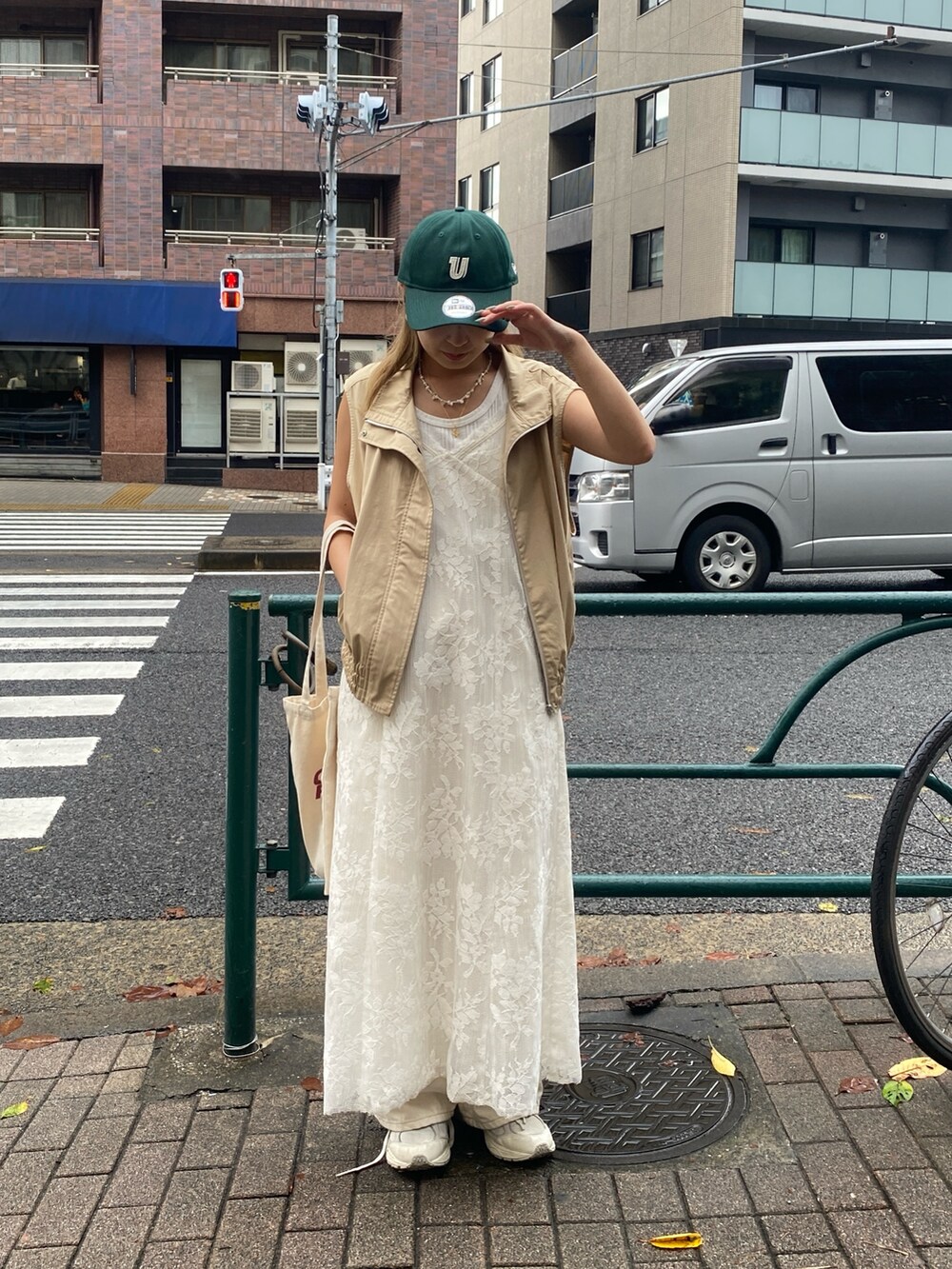 ベージュ系のベスト、ホワイト系のワンピース、ホワイト系のTシャツ/カットソーを着用したレディースの夏コーディネートの2枚目の写真