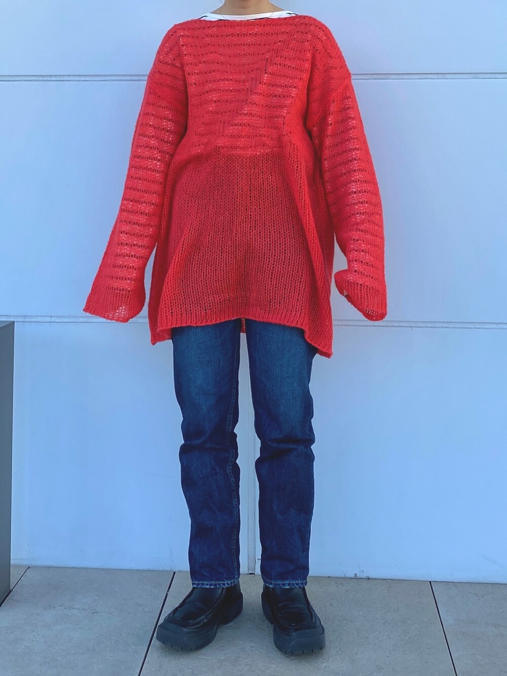 オレンジ系のニット/セーター、ブルー系のTシャツ/カットソーを着用したレディースの冬コーディネートの5枚目の写真