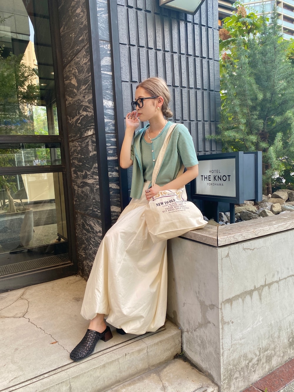 イエロー系のキャミソール、ホワイト系のスカートを着用したレディースの秋コーディネートの4枚目の写真