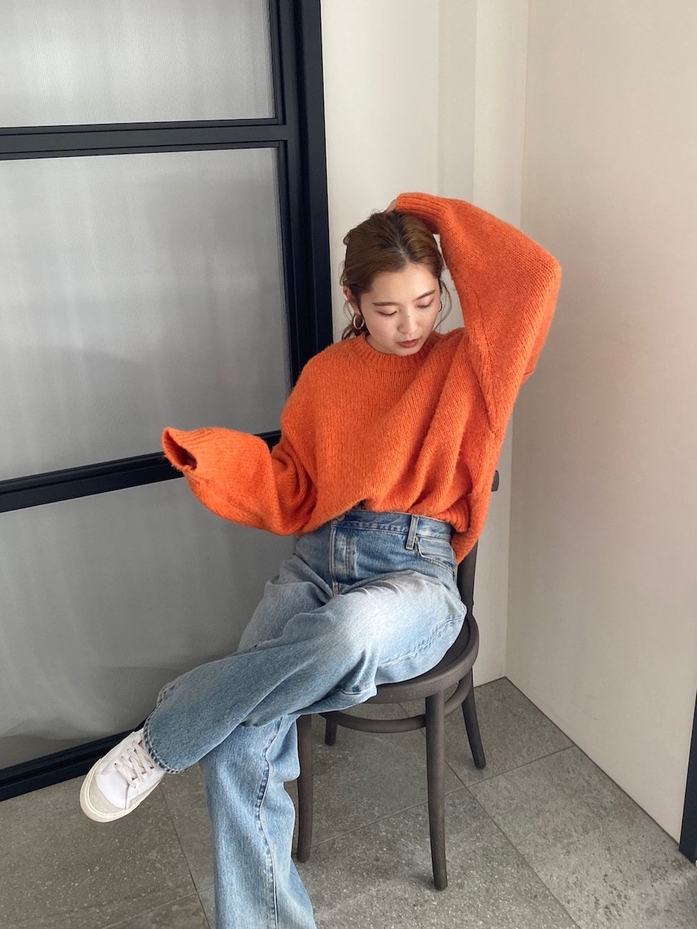 オレンジ系のニット/セーター、ブルー系のデニムパンツを着用したレディースの冬コーディネートの3枚目の写真