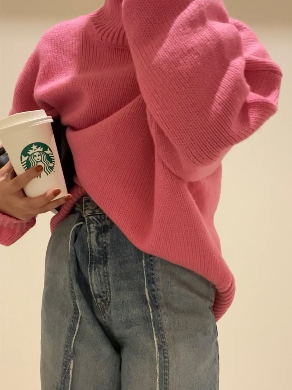 ピンク系のニット/セーター、ブルー系のデニムパンツ、ブラック系のクラッチバッグを着用したレディースの冬コーディネートの3枚目の写真