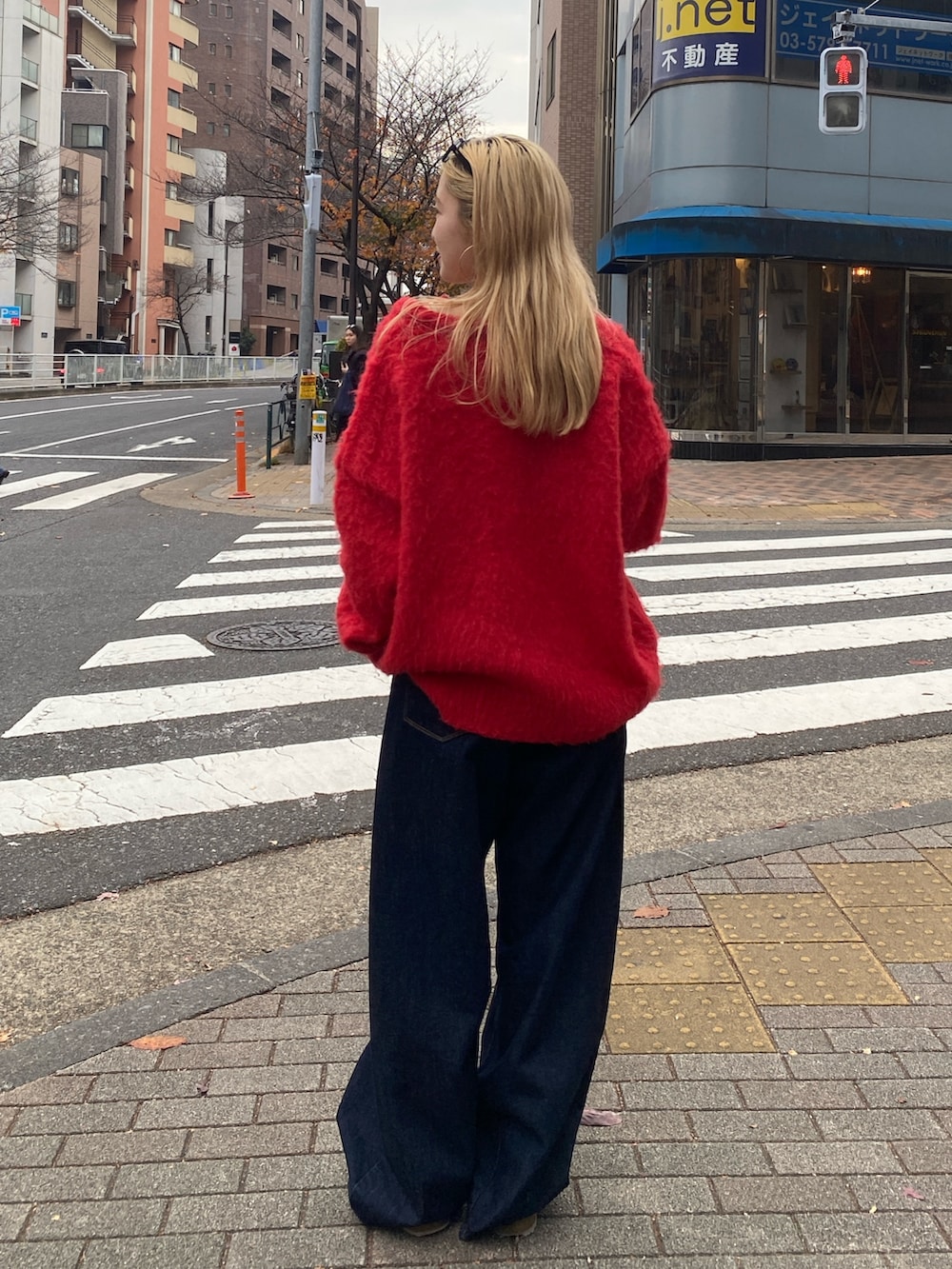 レッド系のニット/セーター、ブルー系のデニムパンツを着用したレディースの冬コーディネートの3枚目の写真