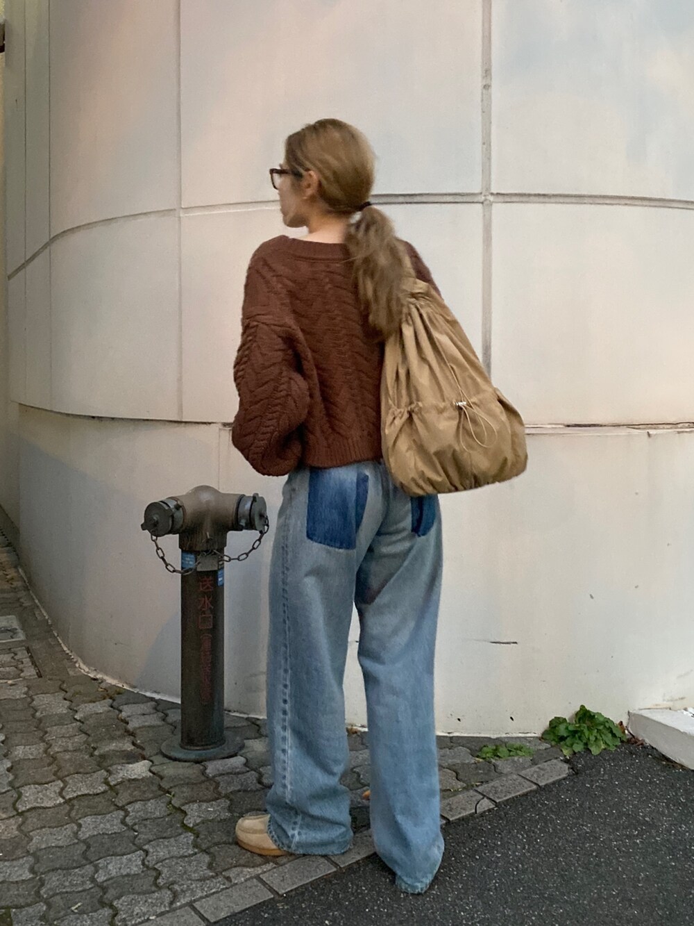 ブラウン系のニット/セーター、ブルー系のデニムパンツ、ベージュ系のハンドバッグを着用したレディースの冬コーディネートの9枚目の写真