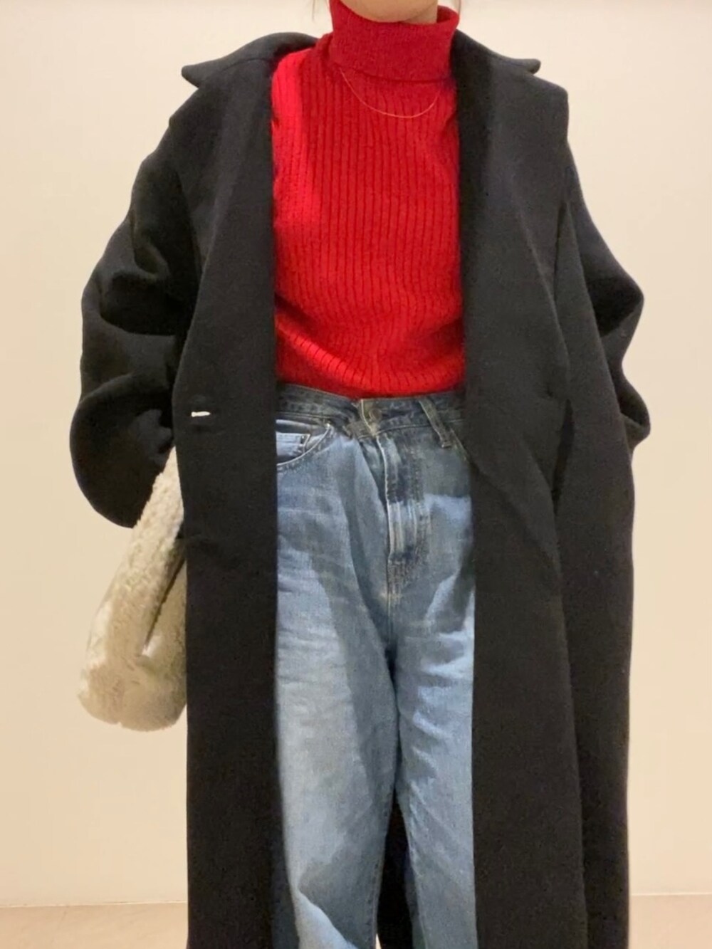 レッド系のニット/セーター、ホワイト系のハンドバッグ、ブラウン系のブーツを着用したレディースの冬コーディネートの3枚目の写真