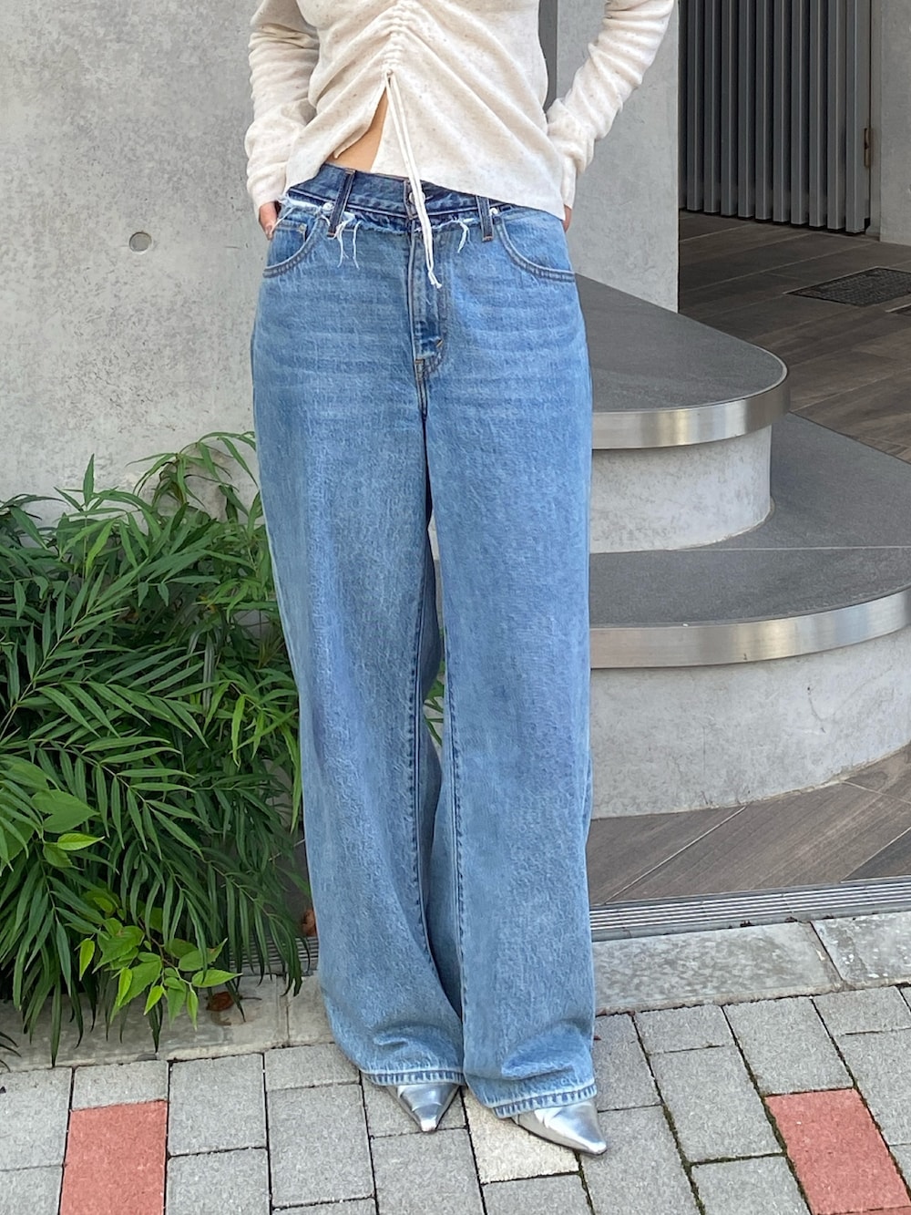 ホワイト系のニット/セーター、ブルー系のデニムパンツ、シルバー系のパンプスを着用したレディースの夏コーディネートの5枚目の写真
