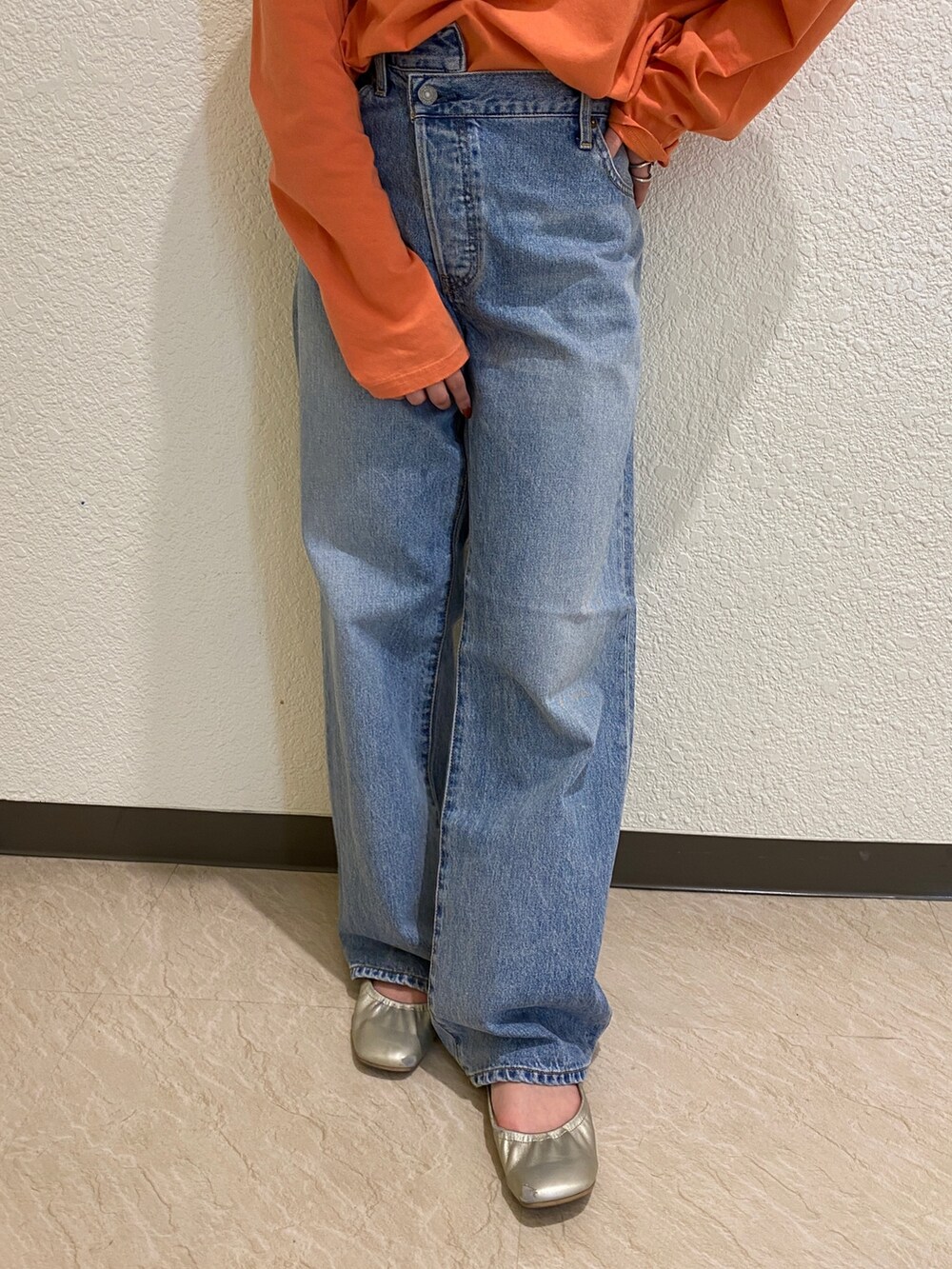 オレンジ系のTシャツ/カットソー、ブルー系のデニムパンツを着用したレディースの冬コーディネートの5枚目の写真