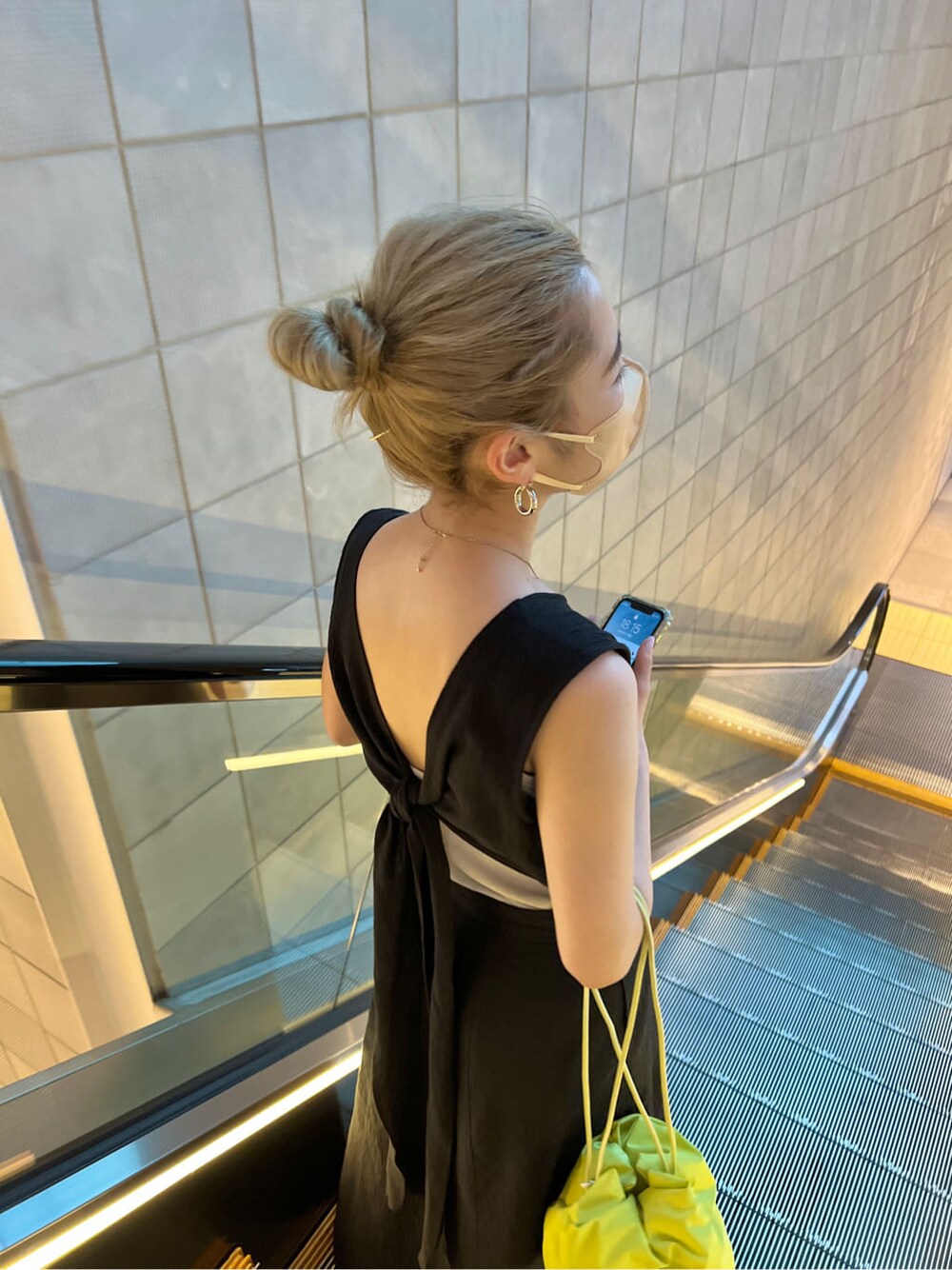 グリーン系のハンドバッグ、ブラック系のワンピースを着用したレディースの春コーディネートの5枚目の写真