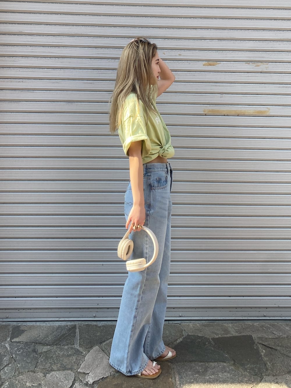 ブルー系のデニムパンツ、グリーン系のTシャツ/カットソー、ホワイト系のサンダルを着用したレディースの春コーディネートの3枚目の写真