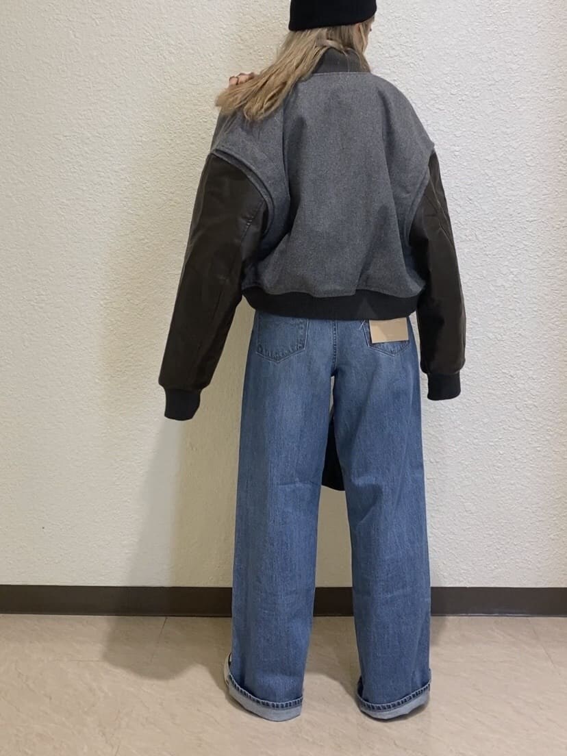 グレー系のブルゾン、ホワイト系のニット/セーター、ブルー系のデニムパンツを着用したレディースの秋コーディネートの4枚目の写真