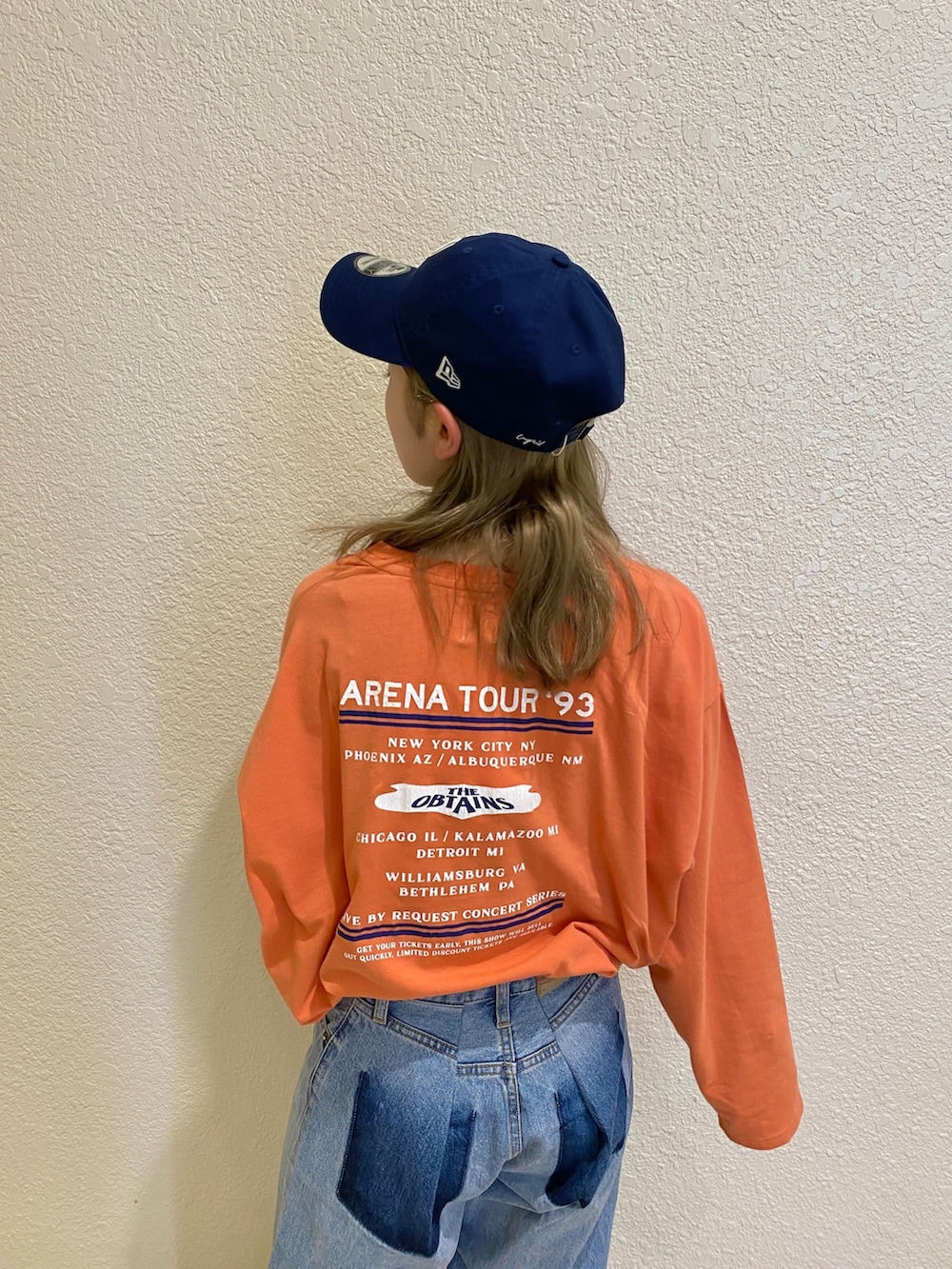 オレンジ系のTシャツ/カットソー、ブルー系のデニムパンツを着用したレディースの冬コーディネートの3枚目の写真